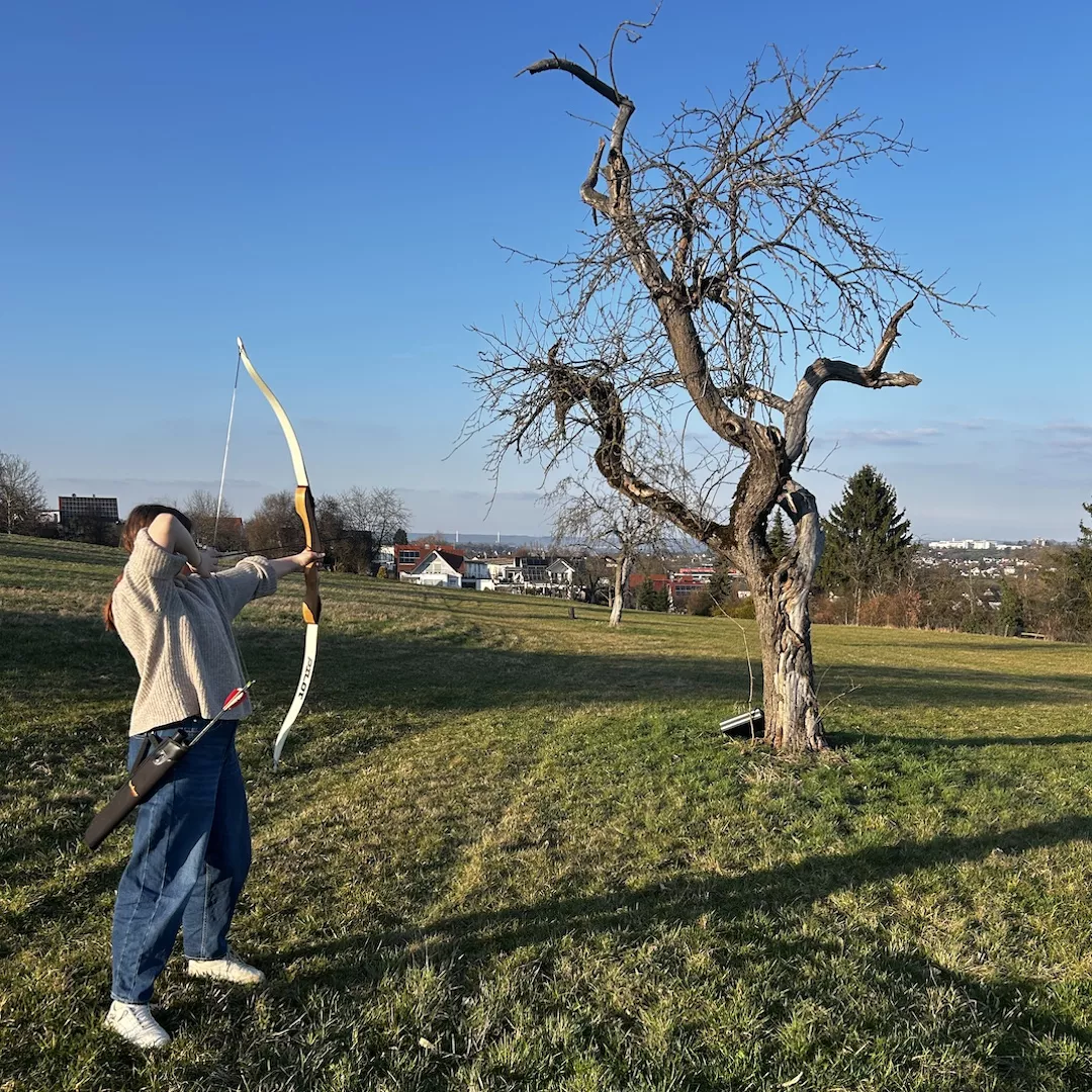 Klientin auf Wiese beim Spannen des Bogens