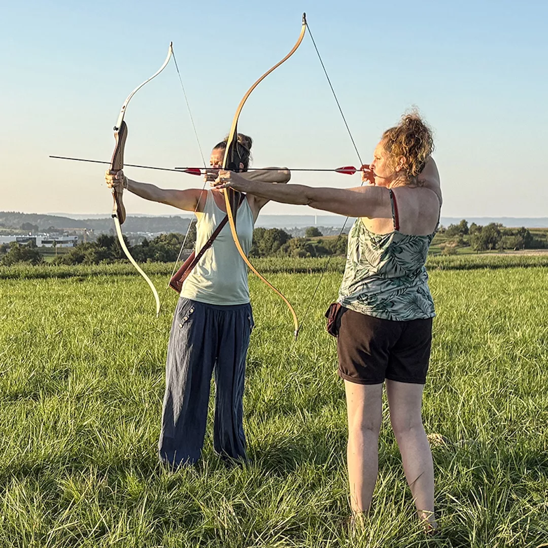 Anja mit Klientin auf Wiese beim Spannen des Bogens