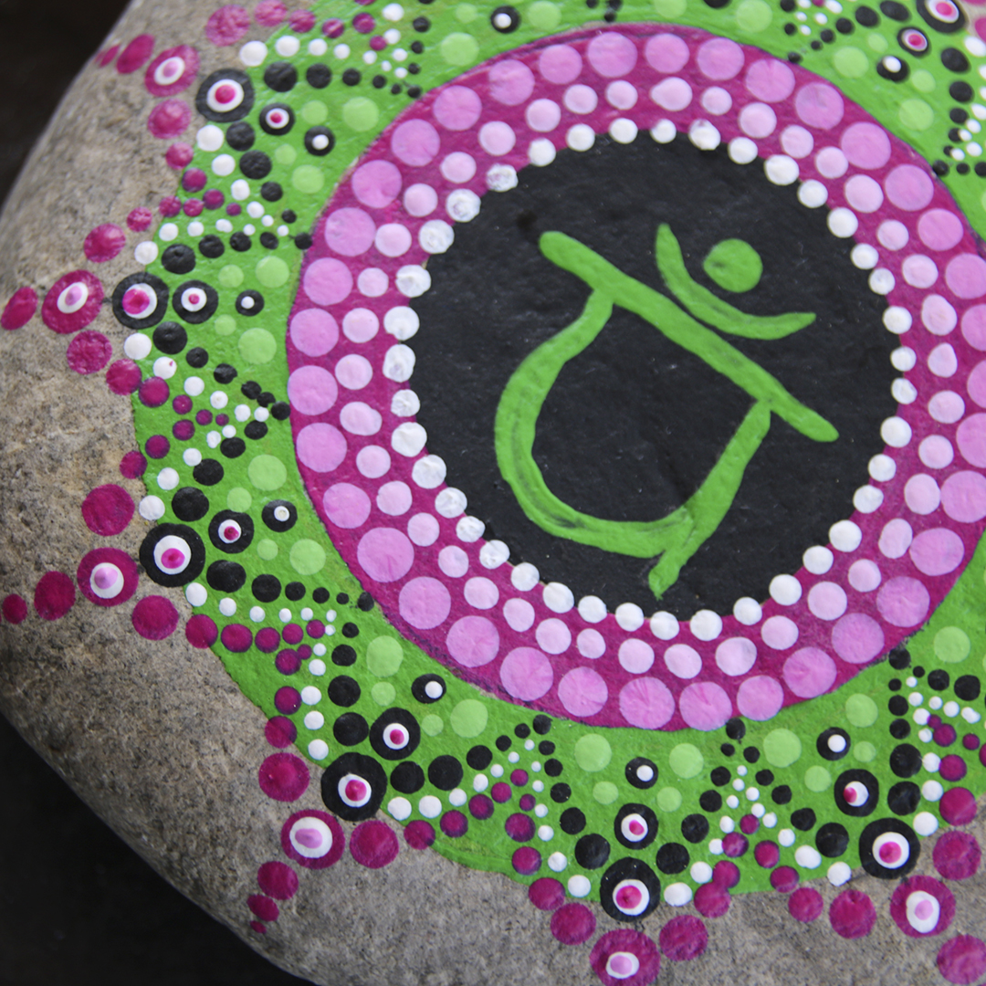 Symbol für Herzchakra mit grünen und rosa Acrylfarben auf Stein gestaltet Nahaufnahme