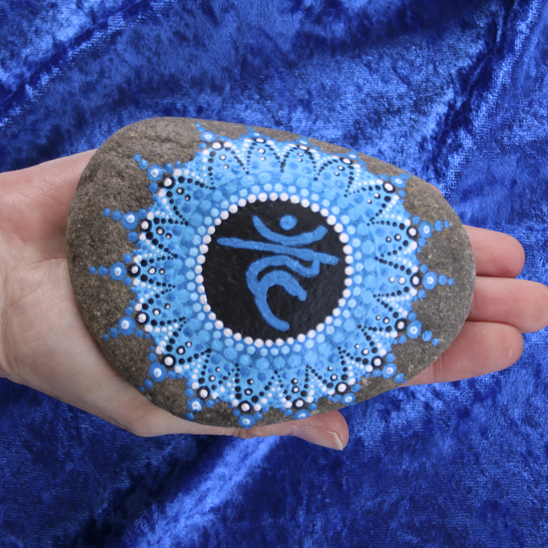 Symbol für Kehlchakra in Blautönen mit Acrylfarbe gestaltet auf Naturstein in der Hand