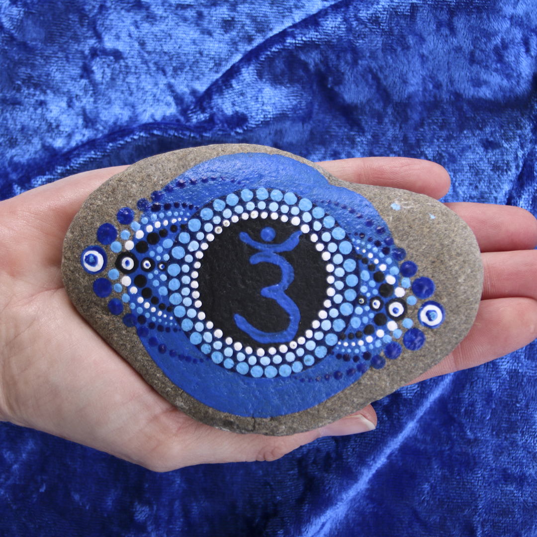 Symbol Stirnchakra in Blautönen mit Acrylfarbe auf Naturstein auf Hand
