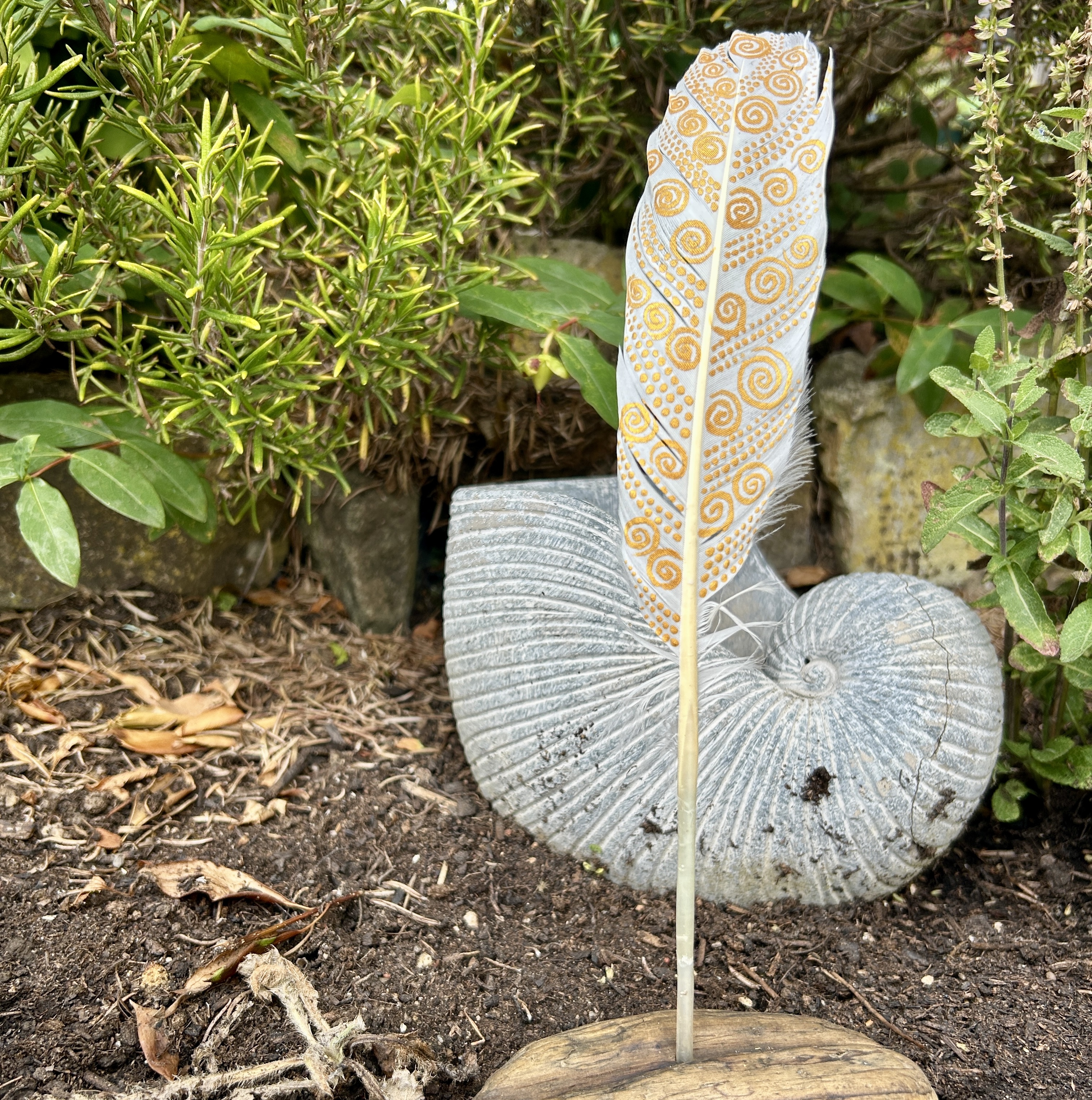 eine mit Gold bemalte Schwanenfeder in einem Holzständer im Garten