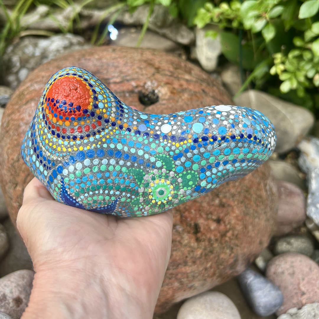 Bemalter Stein mit Sonne, Wasser und Schildkröte in der Hand gehalten