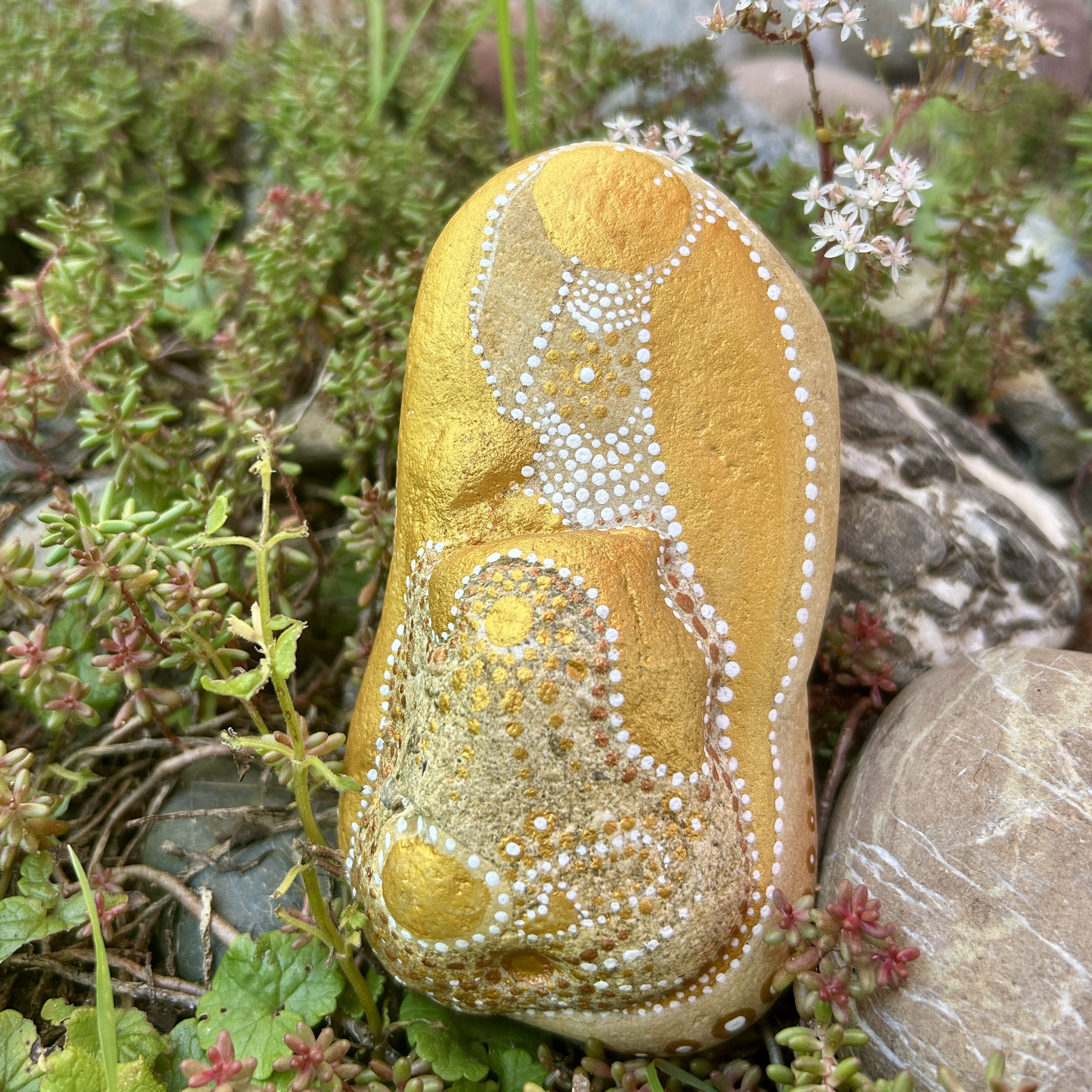 Bemalter Stein mit einem Engel vor Steingarten