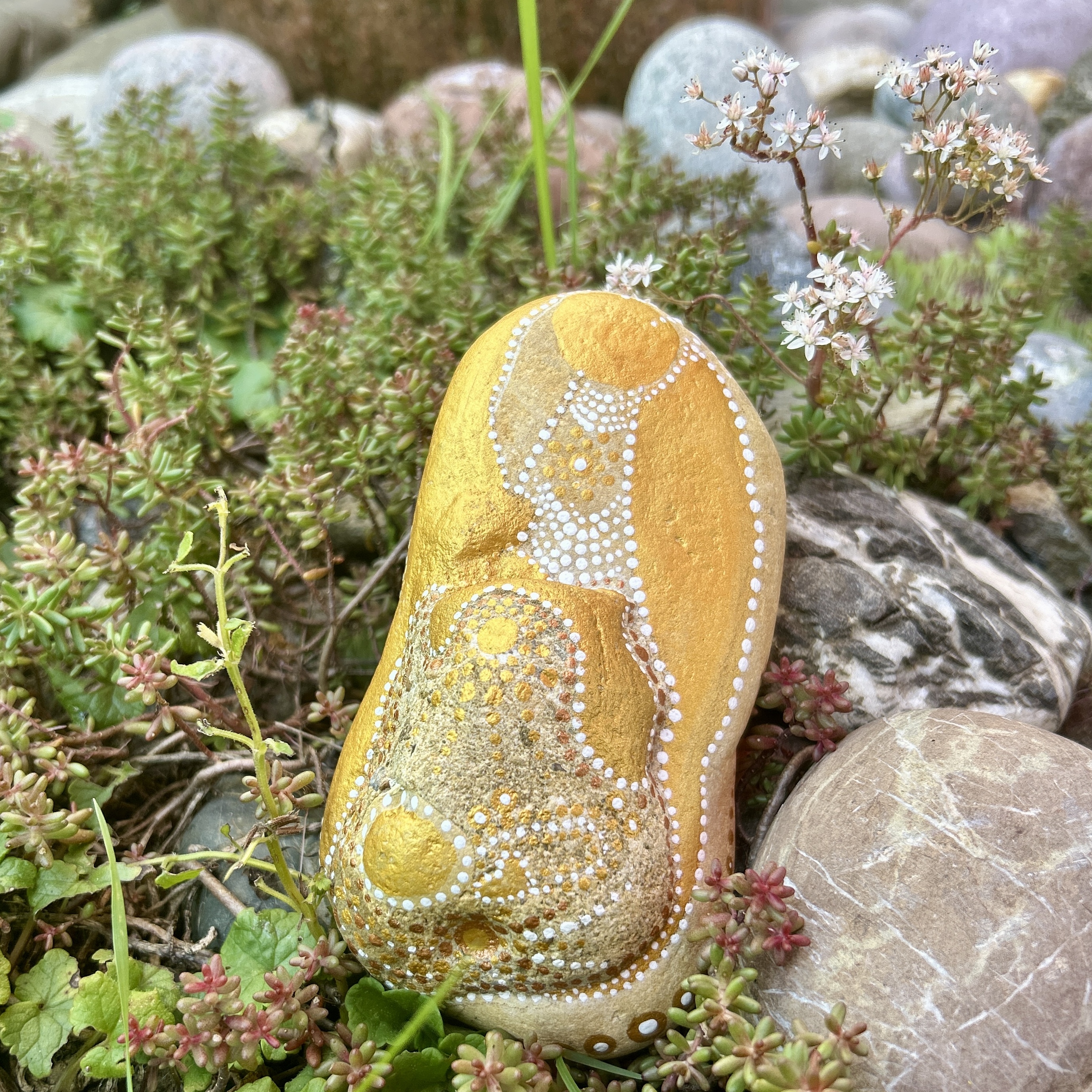Bemalter Stein mit einem Engel vor Steingarten