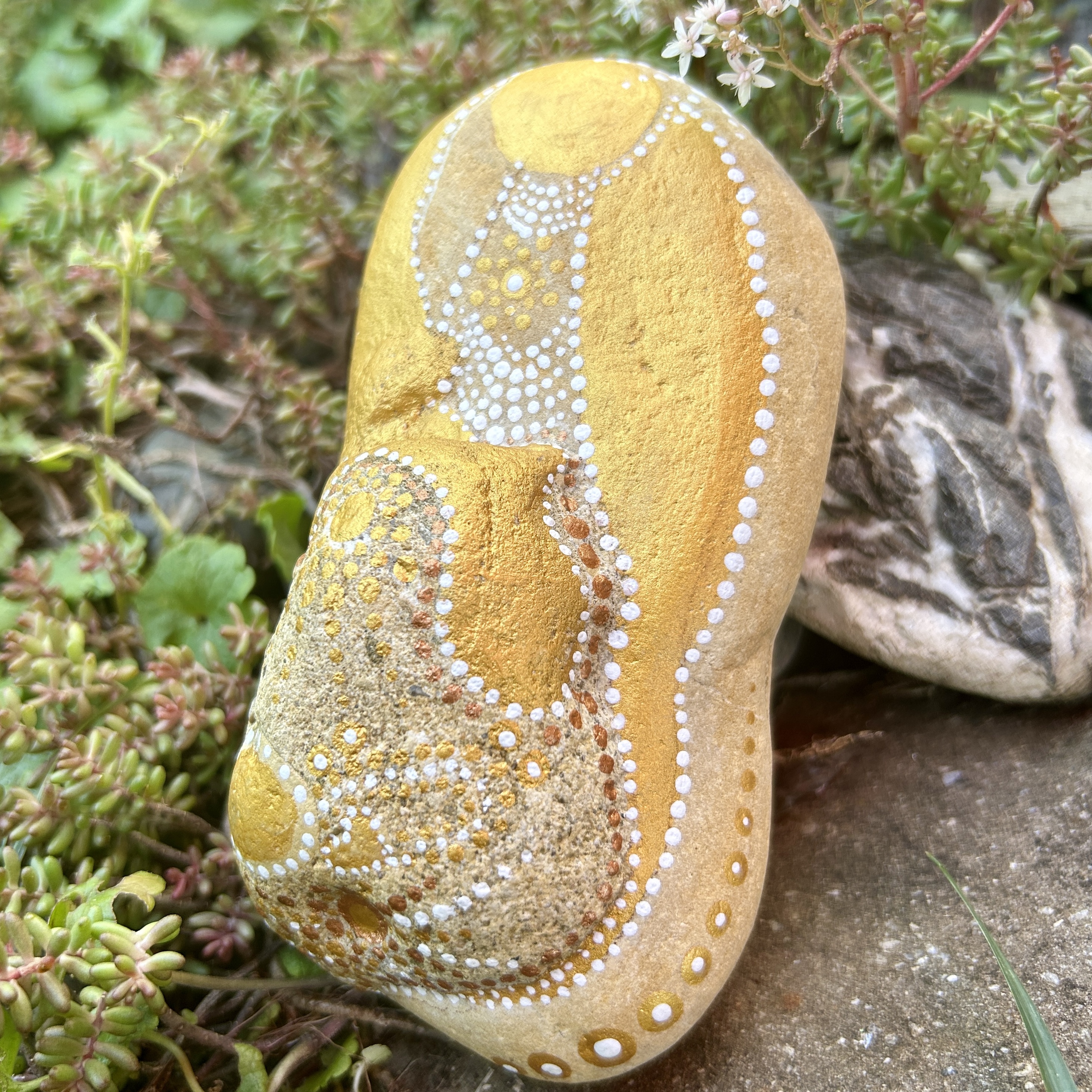 Bemalter Stein mit einem Engel vor Steingarten