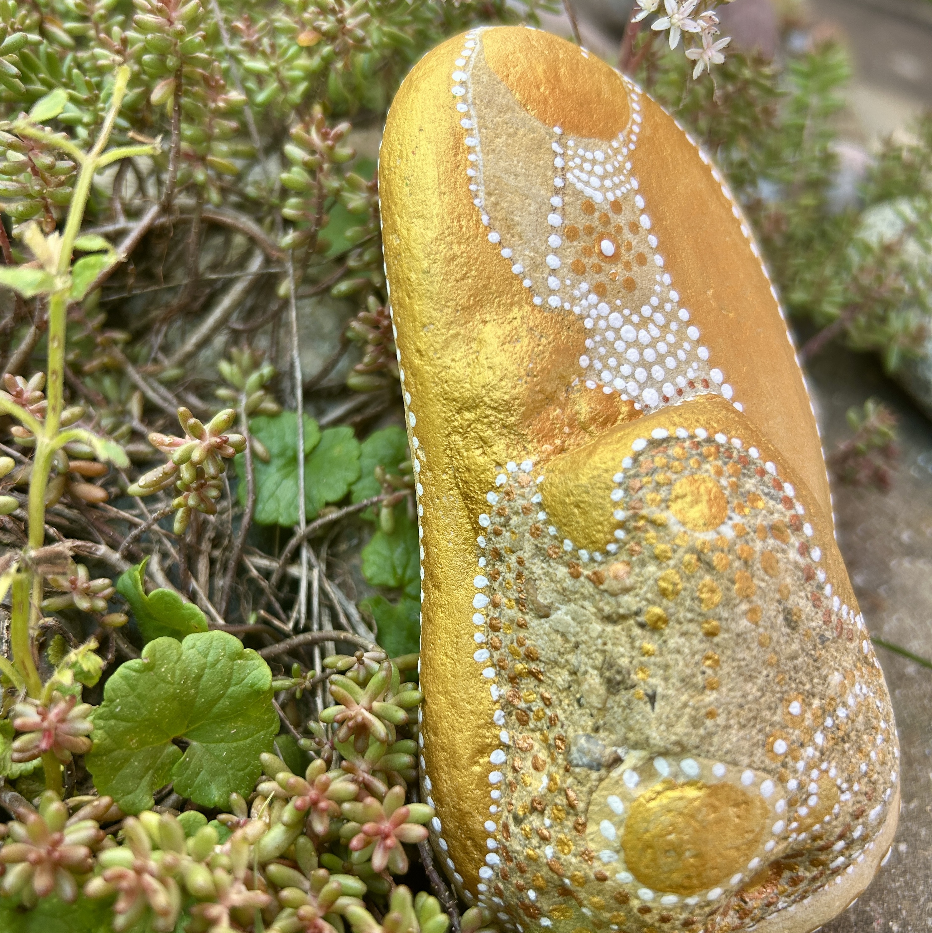 Bemalter Stein mit einem Engel vor Steingarten