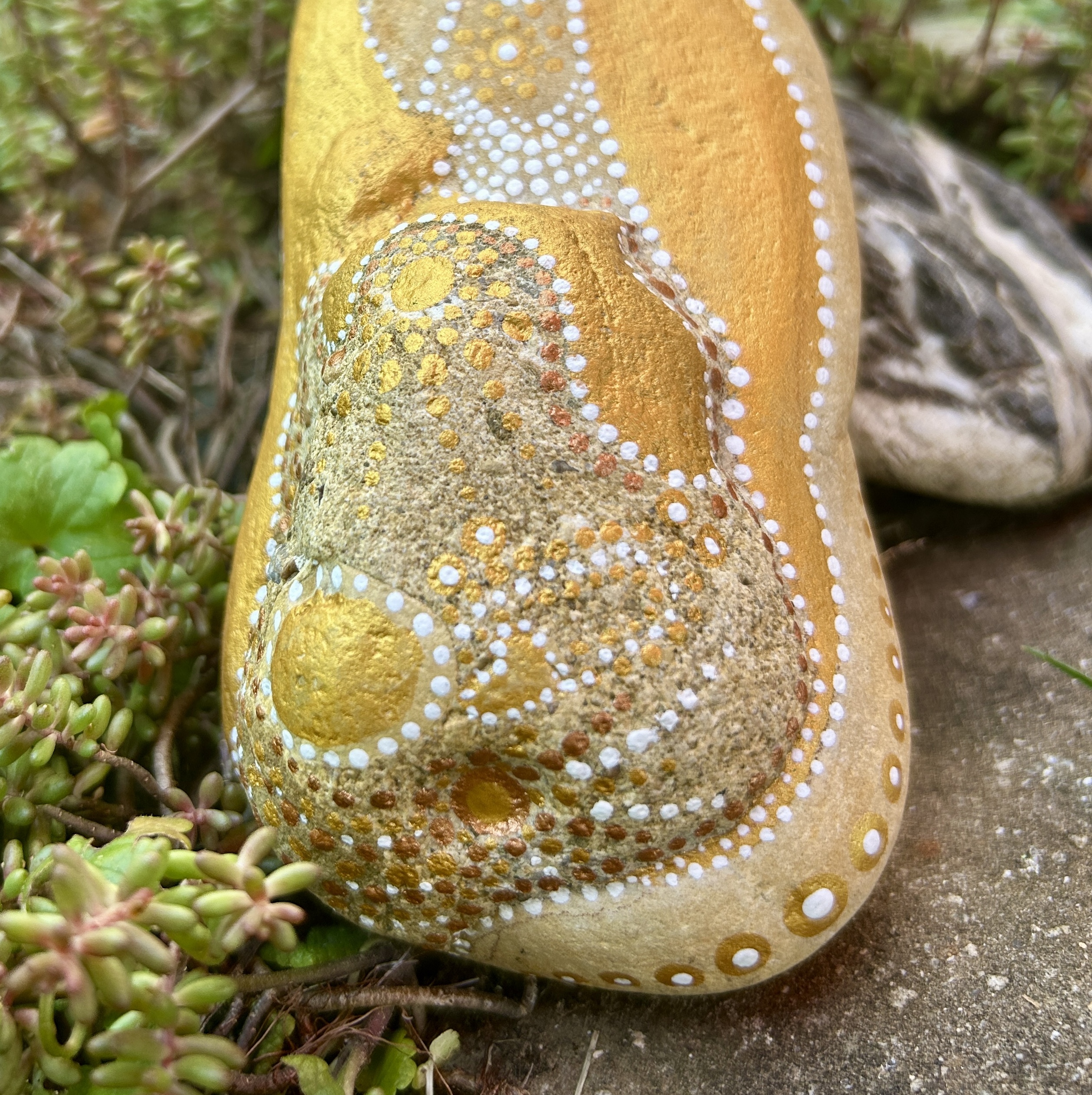 Bemalter Stein mit einem Engel in Naufnahme vor Steingarten