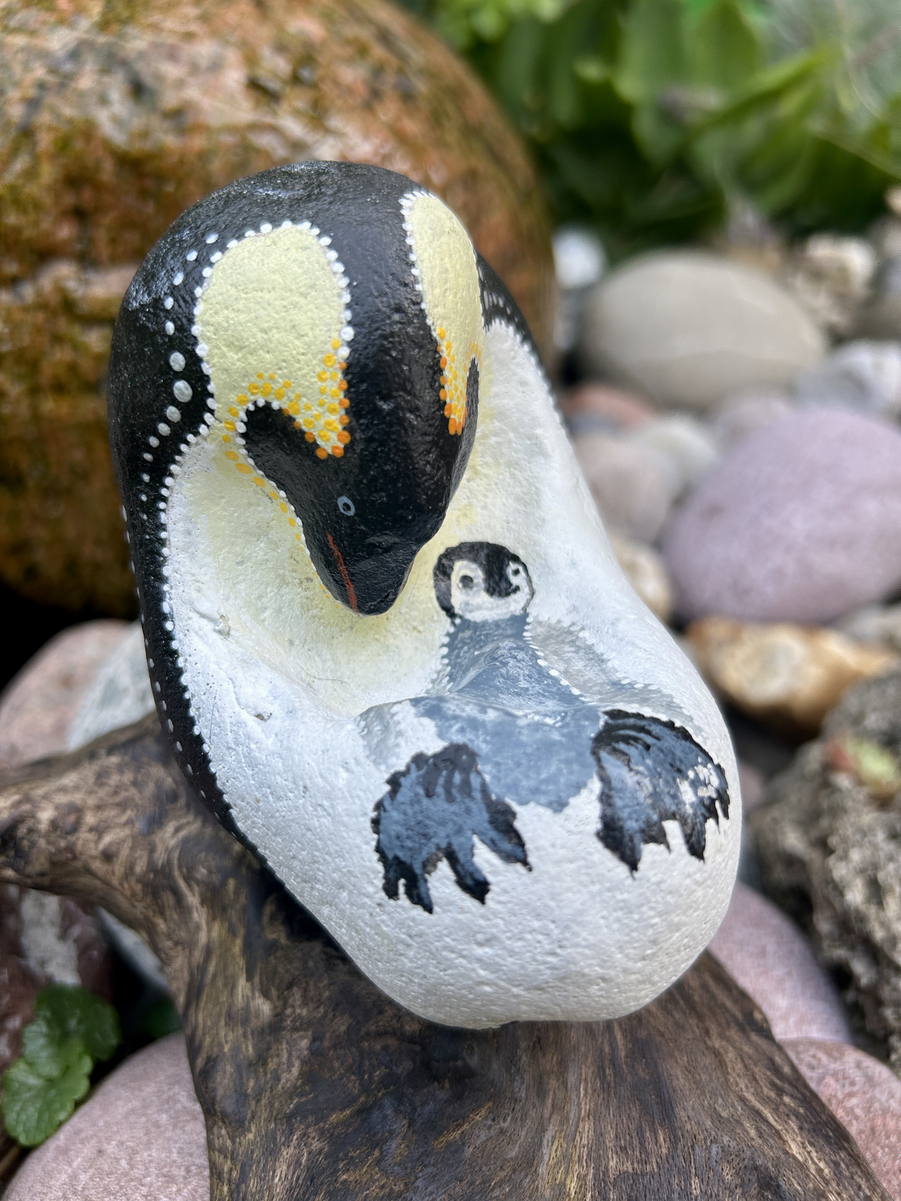 Bemalter Stein mit Pinguin und Junges auf einem Treibholzständer