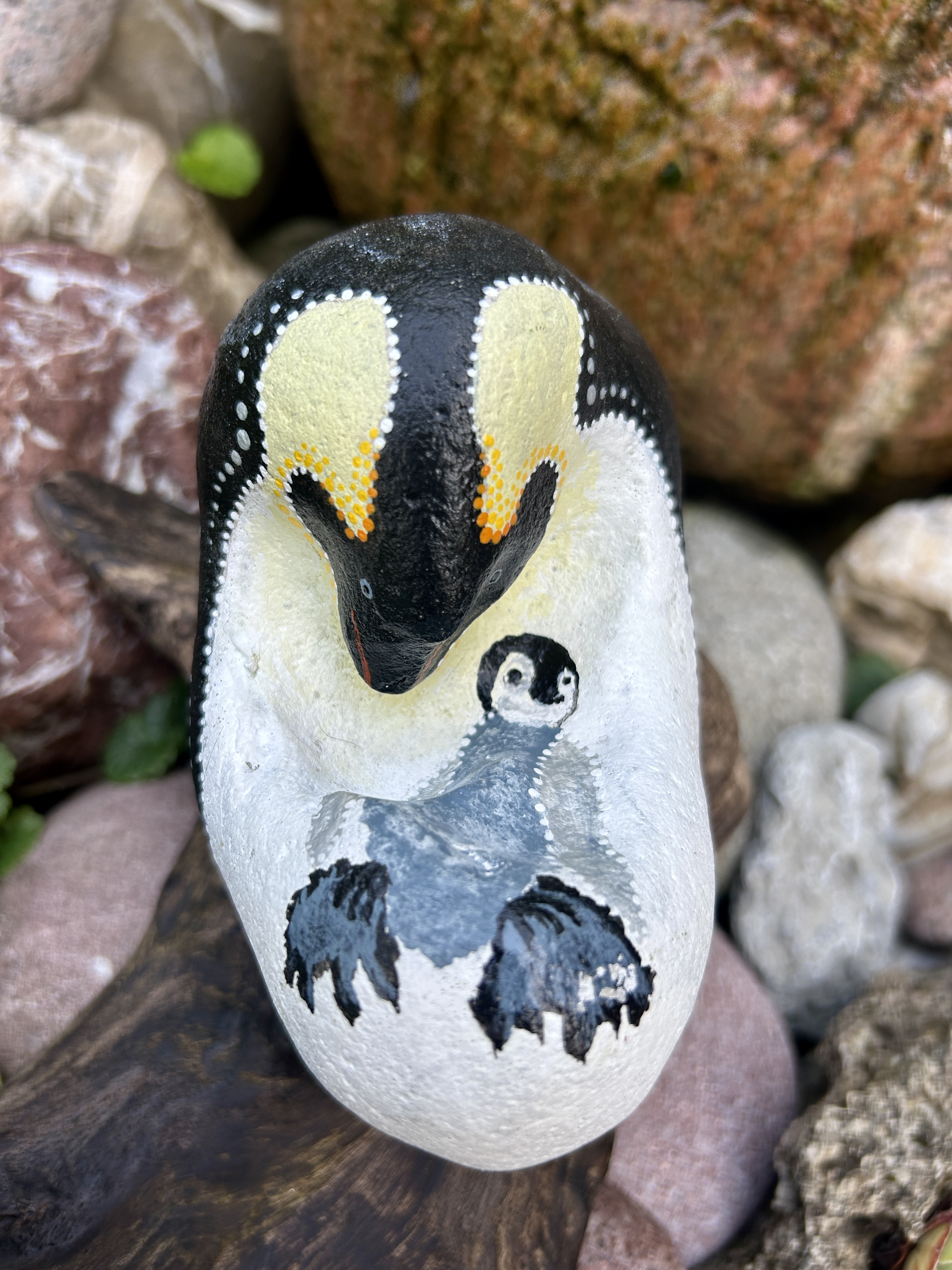 Bemalter Stein mit Pinguin und Junges auf einem Treibholzständer
