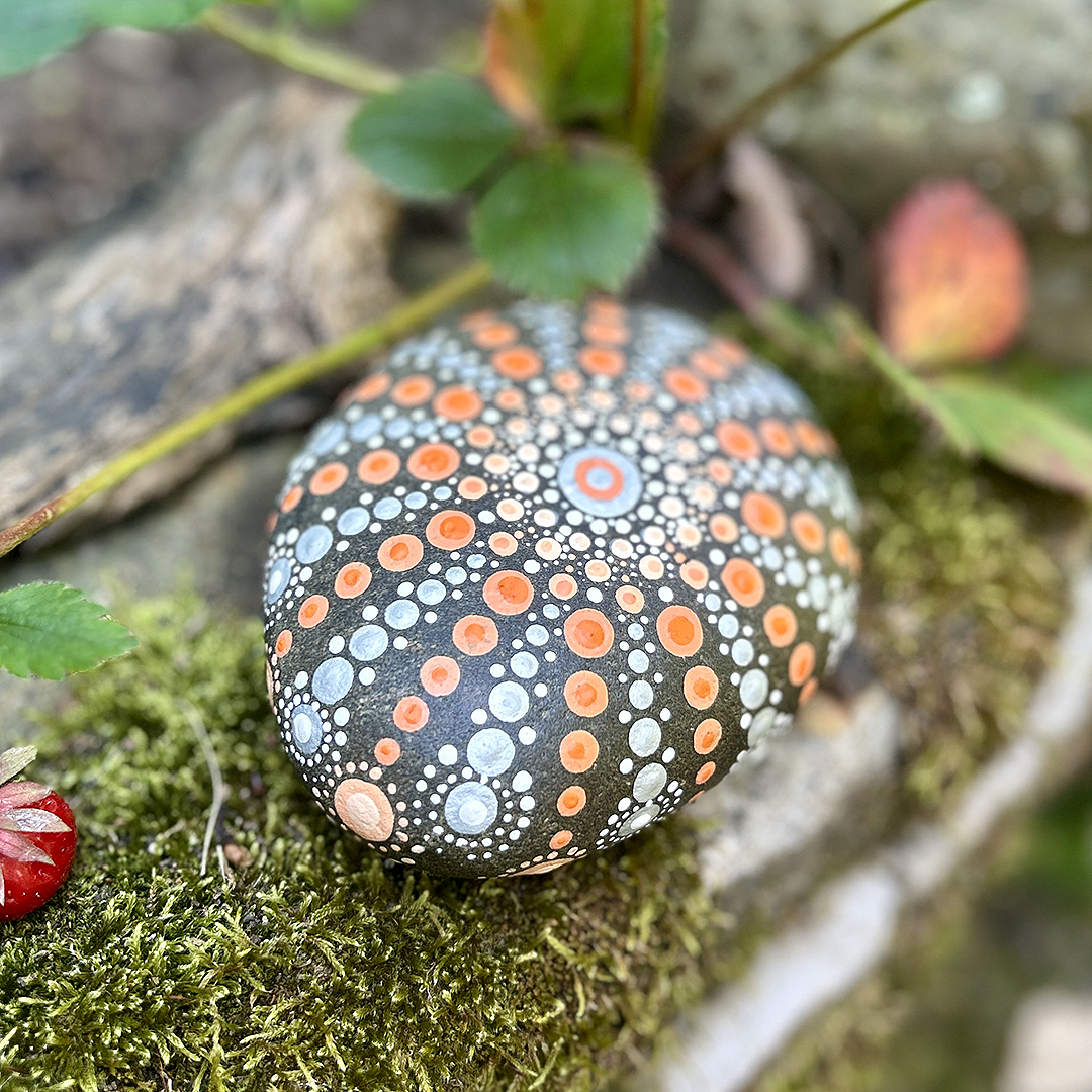Bemalter Stein mit Mandala auf Moos liegend