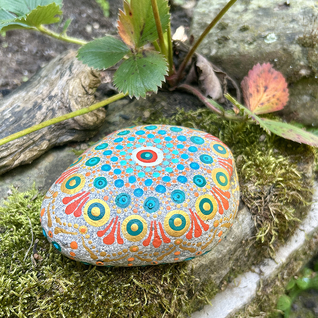 Bemalter Stein mit Mandala auf Moos