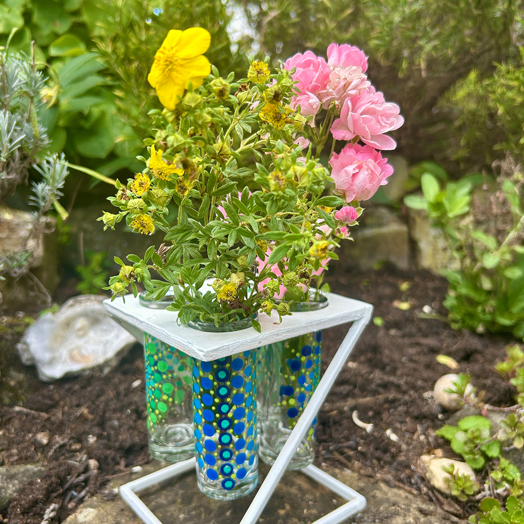 Glasvasen bemalt mit Mandalas in Grün und Blau mit gelben und rosa Blumen darin
