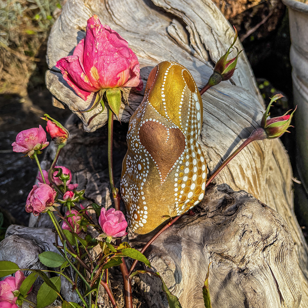 Bemalter Stein in weiß und Gold mit Rosen auf einer Wurzel