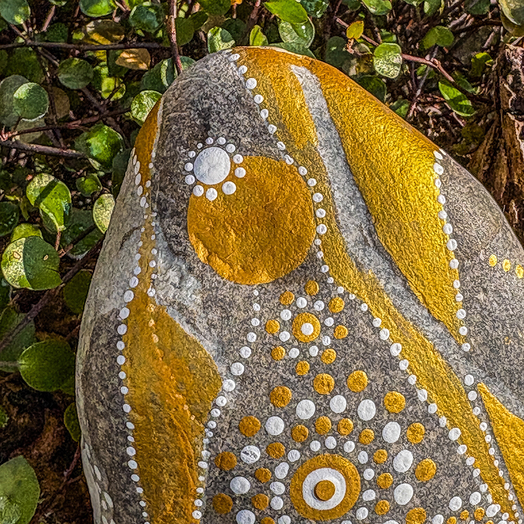 Nahaufnahme von einem Stein bemalt mit einem Engel in Gold und Weiß