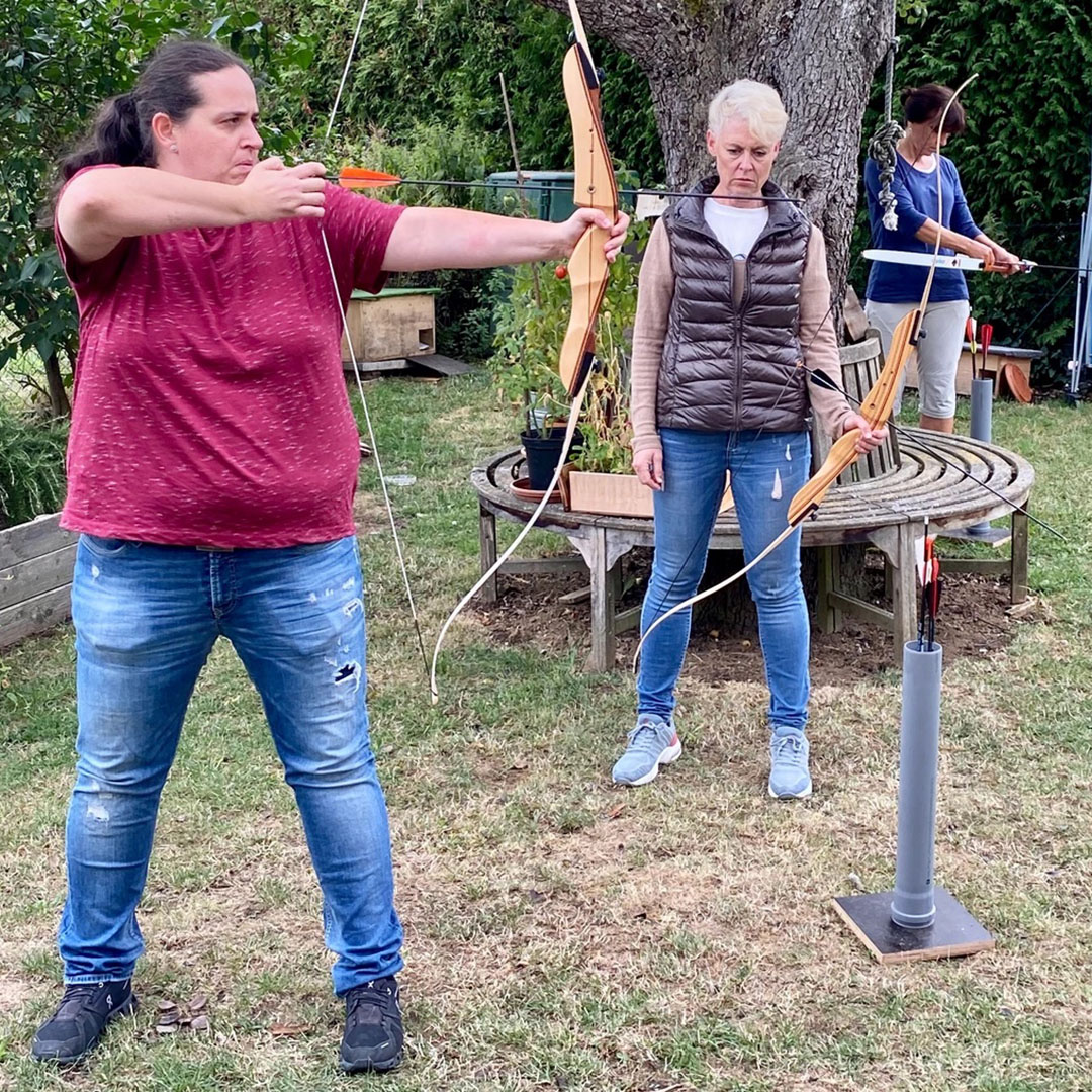 Zwei Frauen beim Bogenschießen im Garten