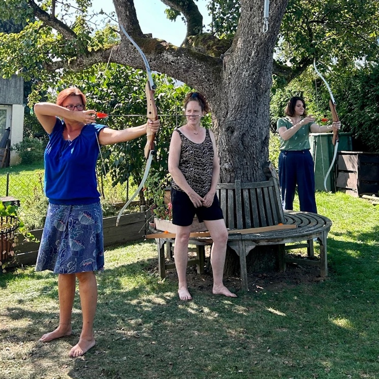 Zwei Frauen beim Bogenschießen im Garten