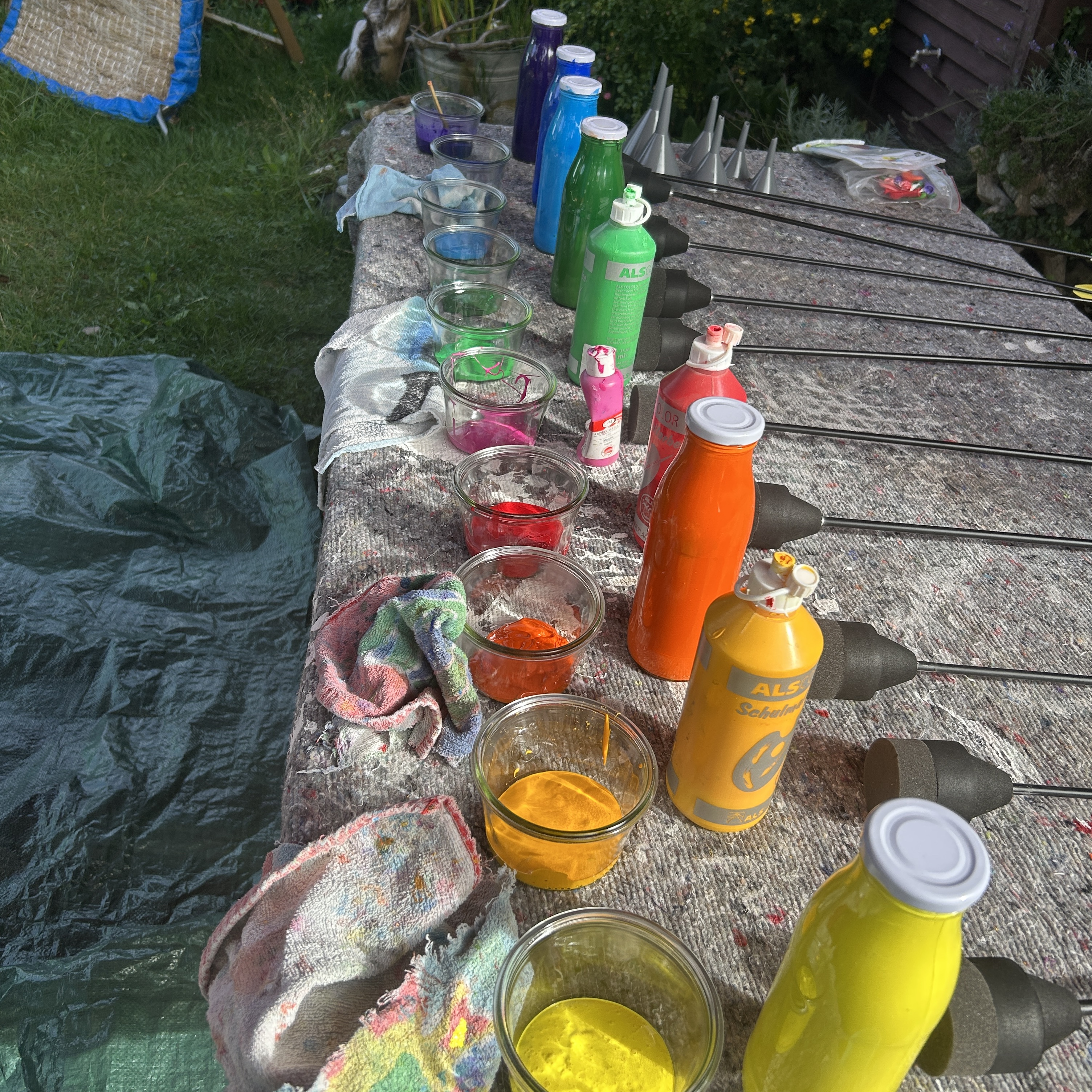 Farbflaschen und Gefäße auf Tisch im Garten