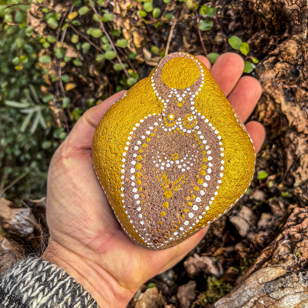 Bemalter Stein mit einem weiblichen Engel liegend in einer Hand