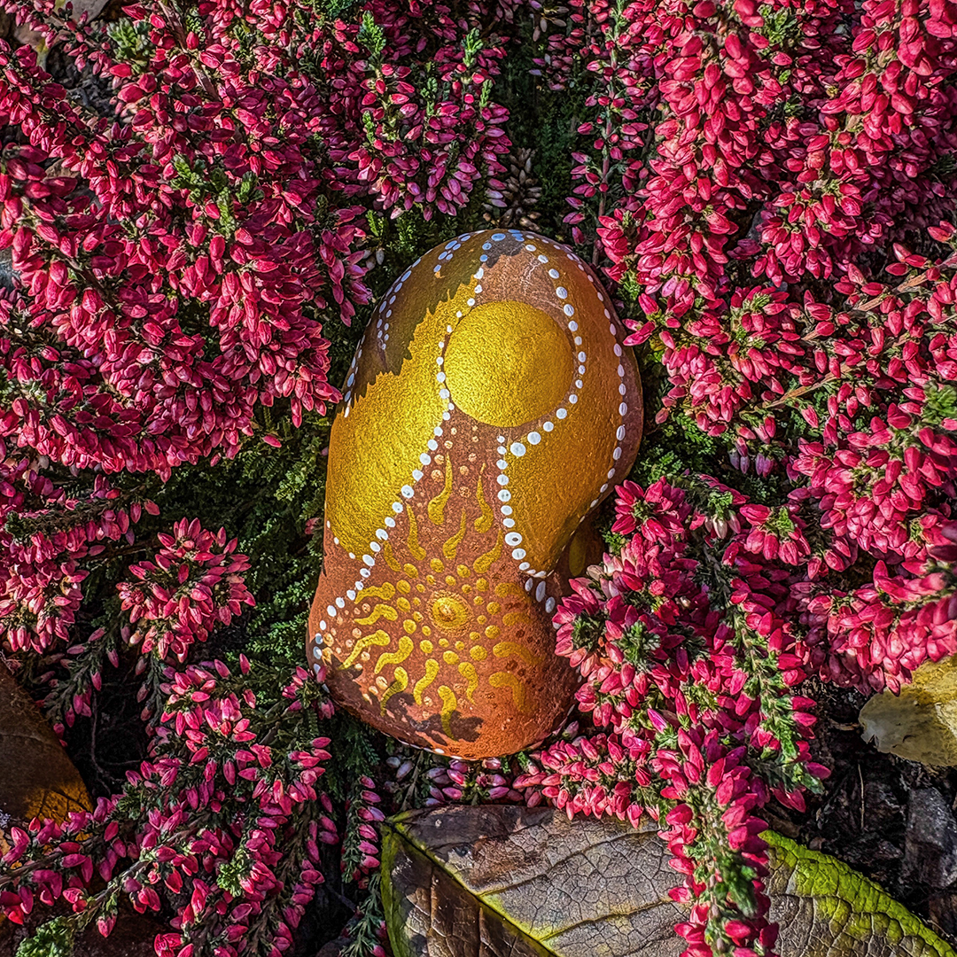 Bemalter Stein mit Engel in roter Erikapflanze