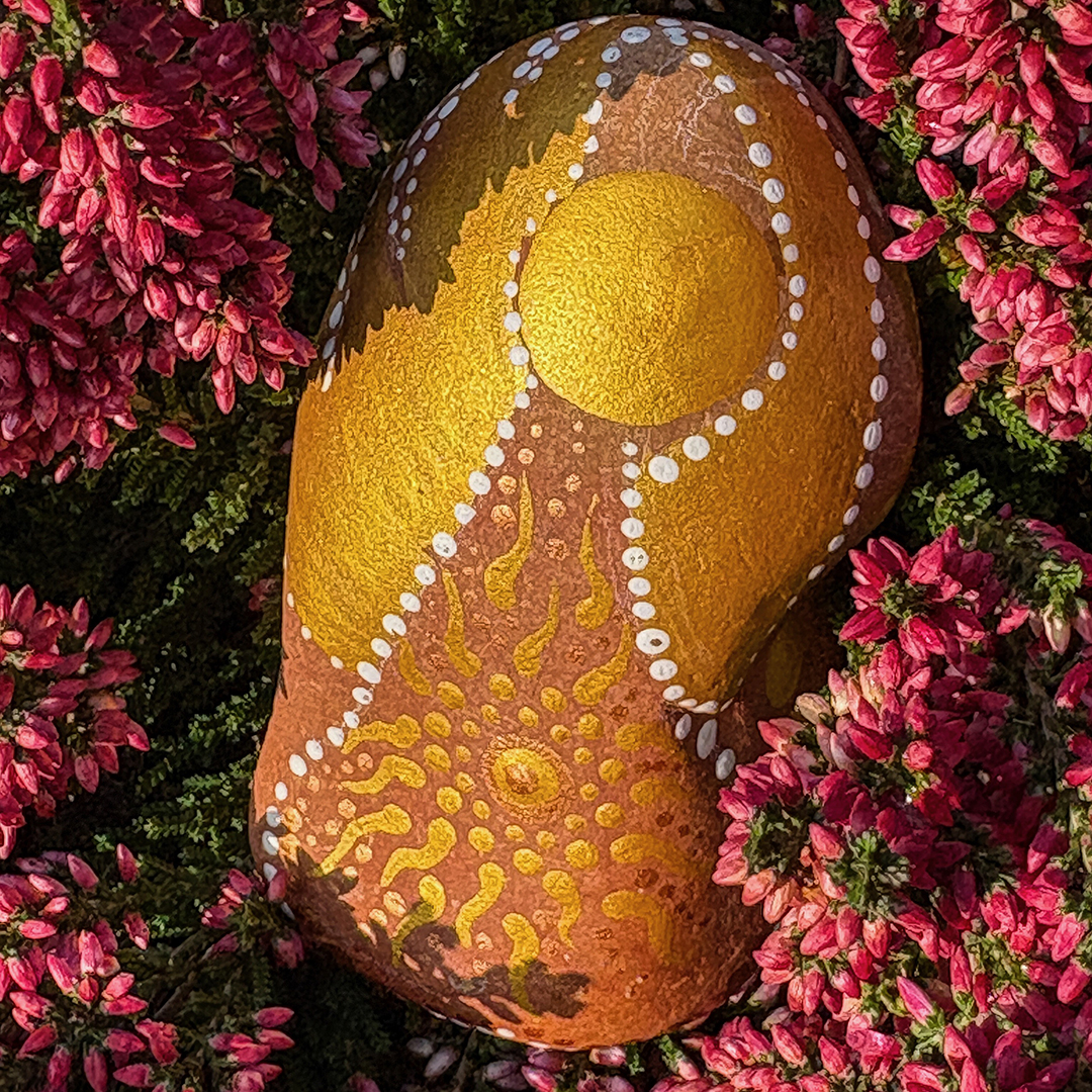 Bemalter Stein mit Engel in roter Erikapflanze