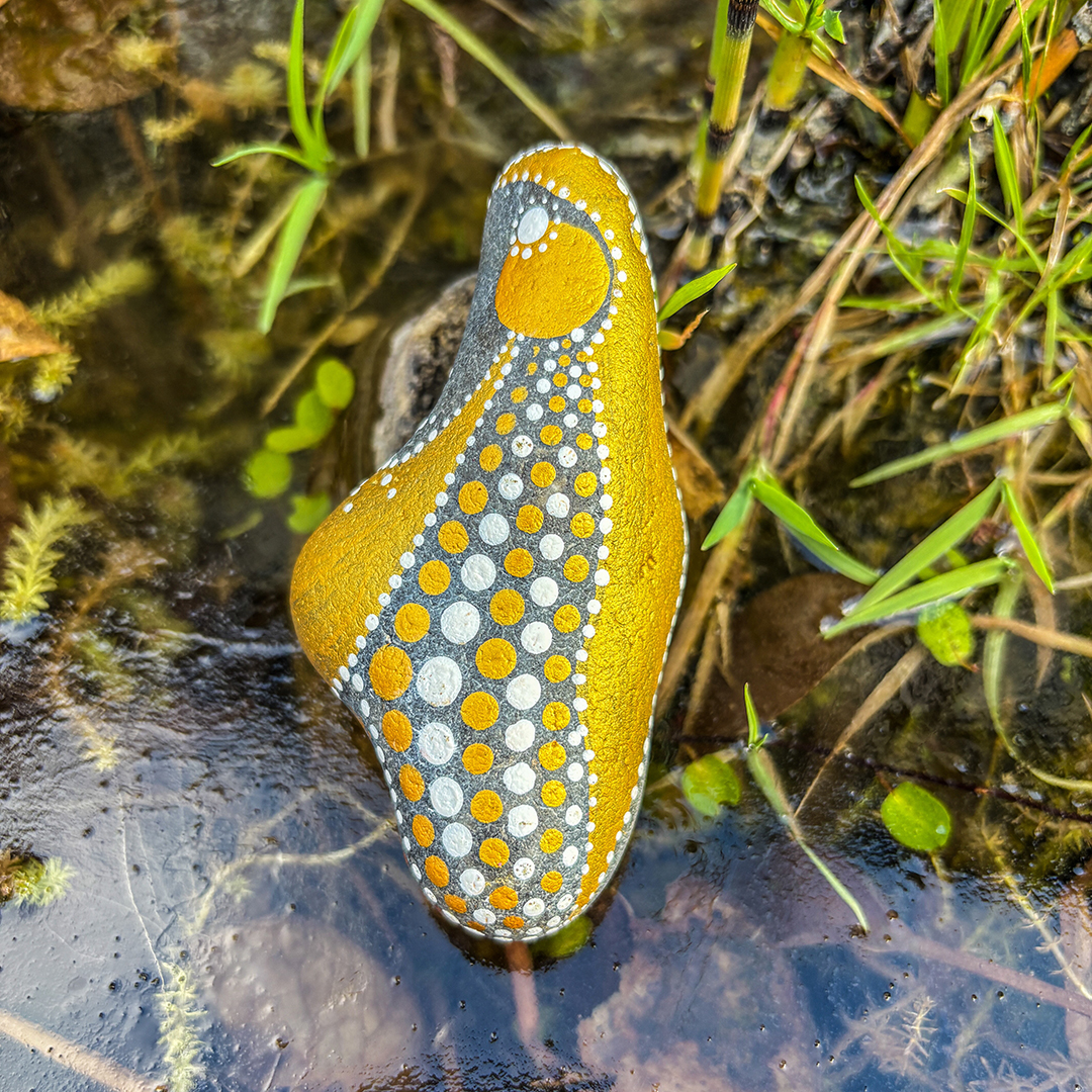 Mit einem Engel bemalter Stein vor Gras
