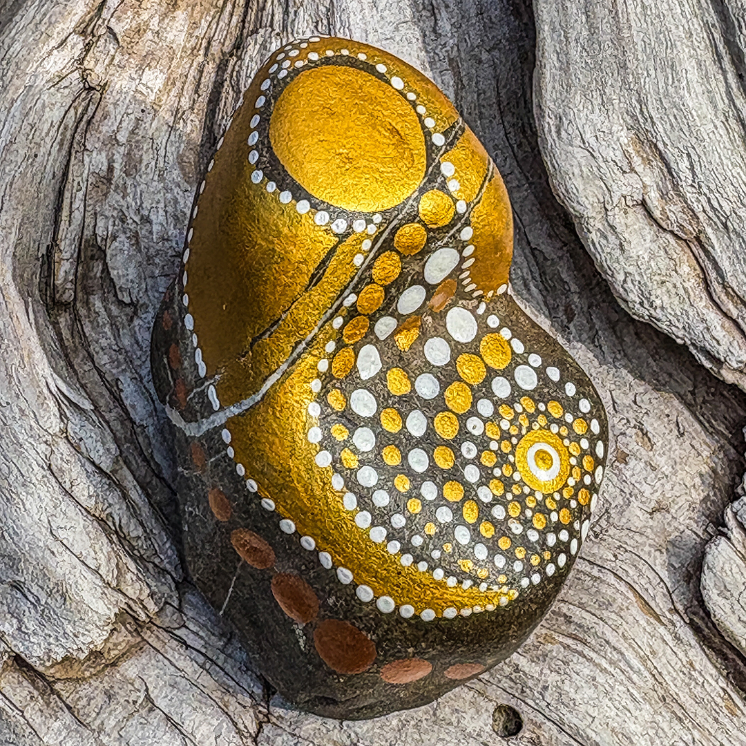 Bemalter Stein mit Engel auf Holz liegend
