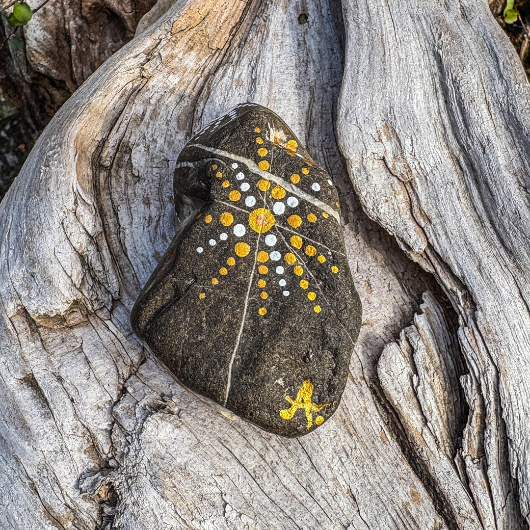 In Dot Painting Bemalter Stein auf Holz liegend