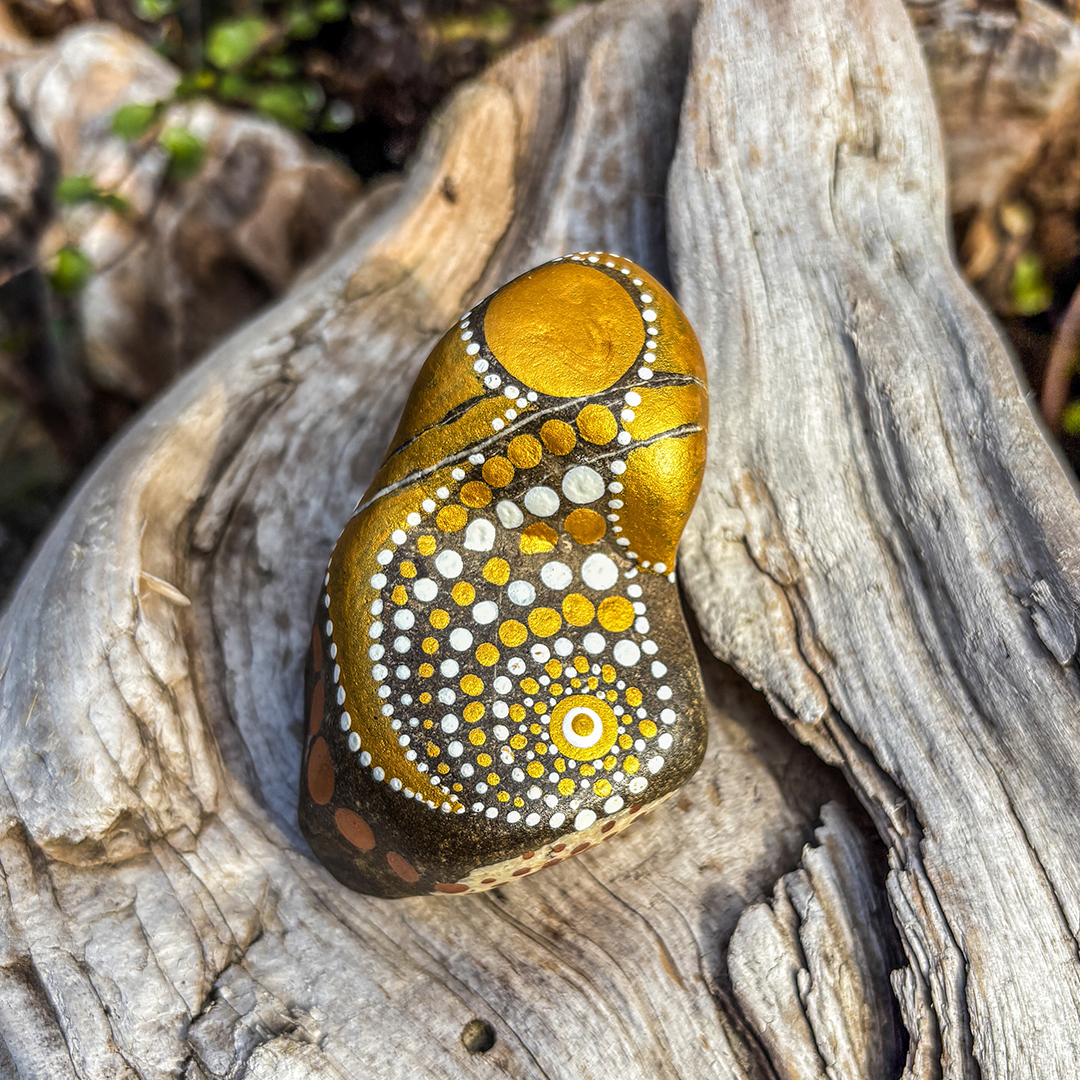 Bemalter Stein mit Engel auf Holz liegend