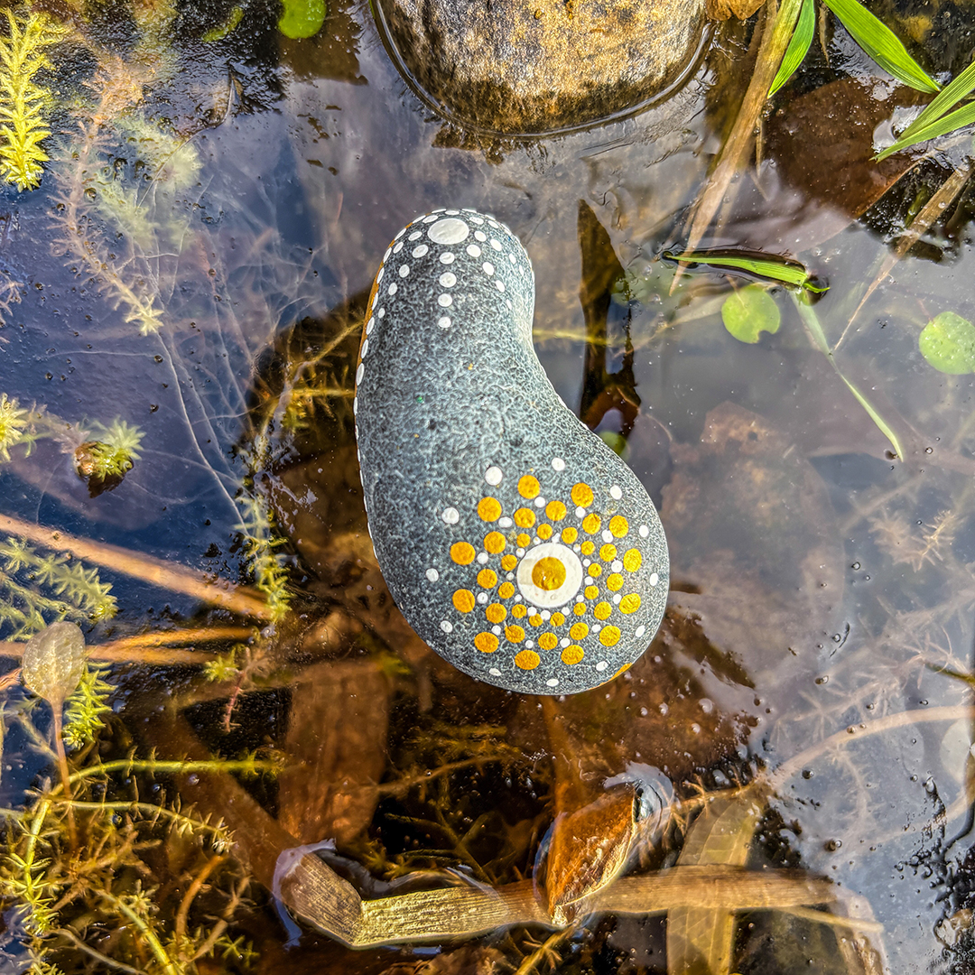 In Dot Painting Technik bemalter Stein auf Eisfläche
