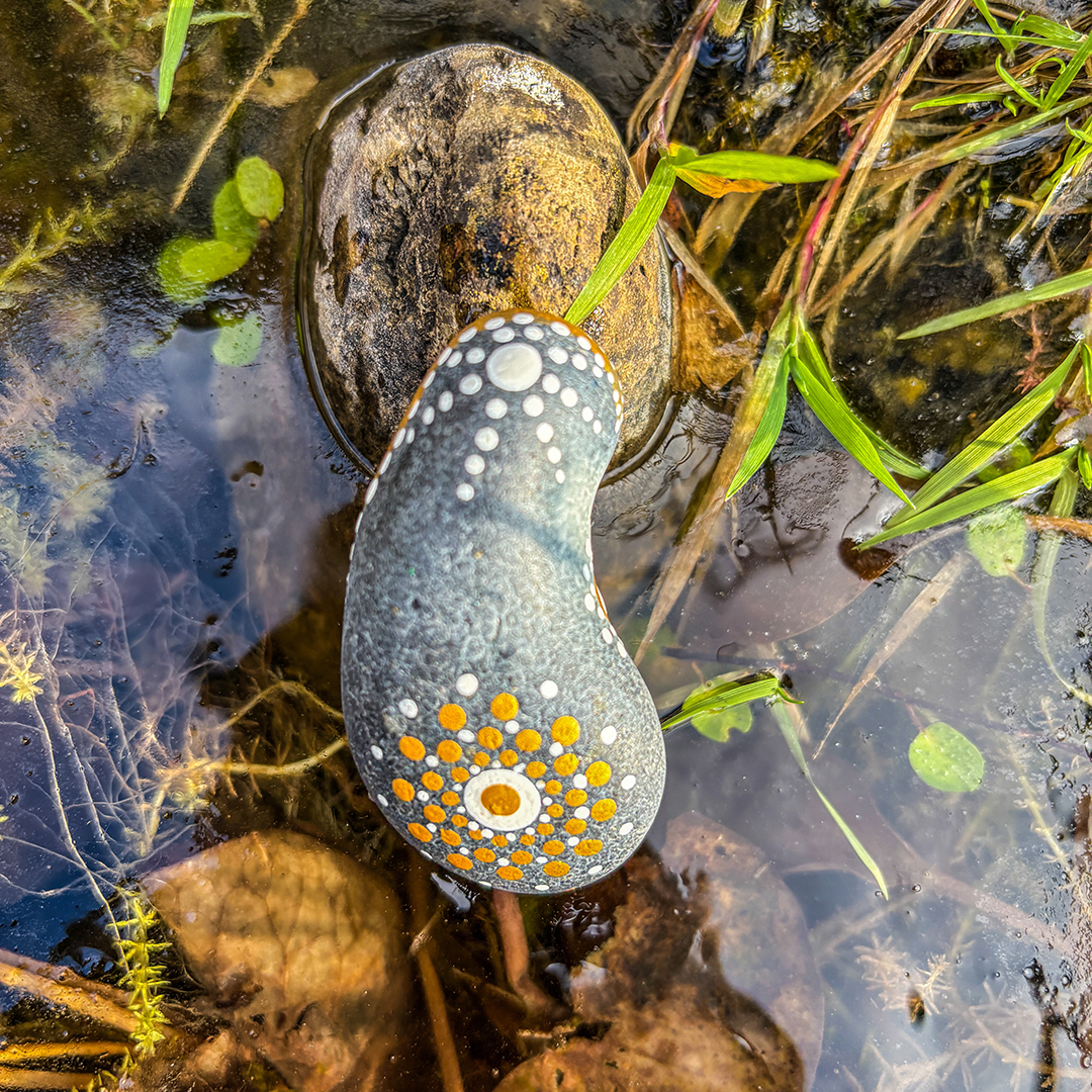 In Dot Painting Technik bemalter Stein auf Eisfläche