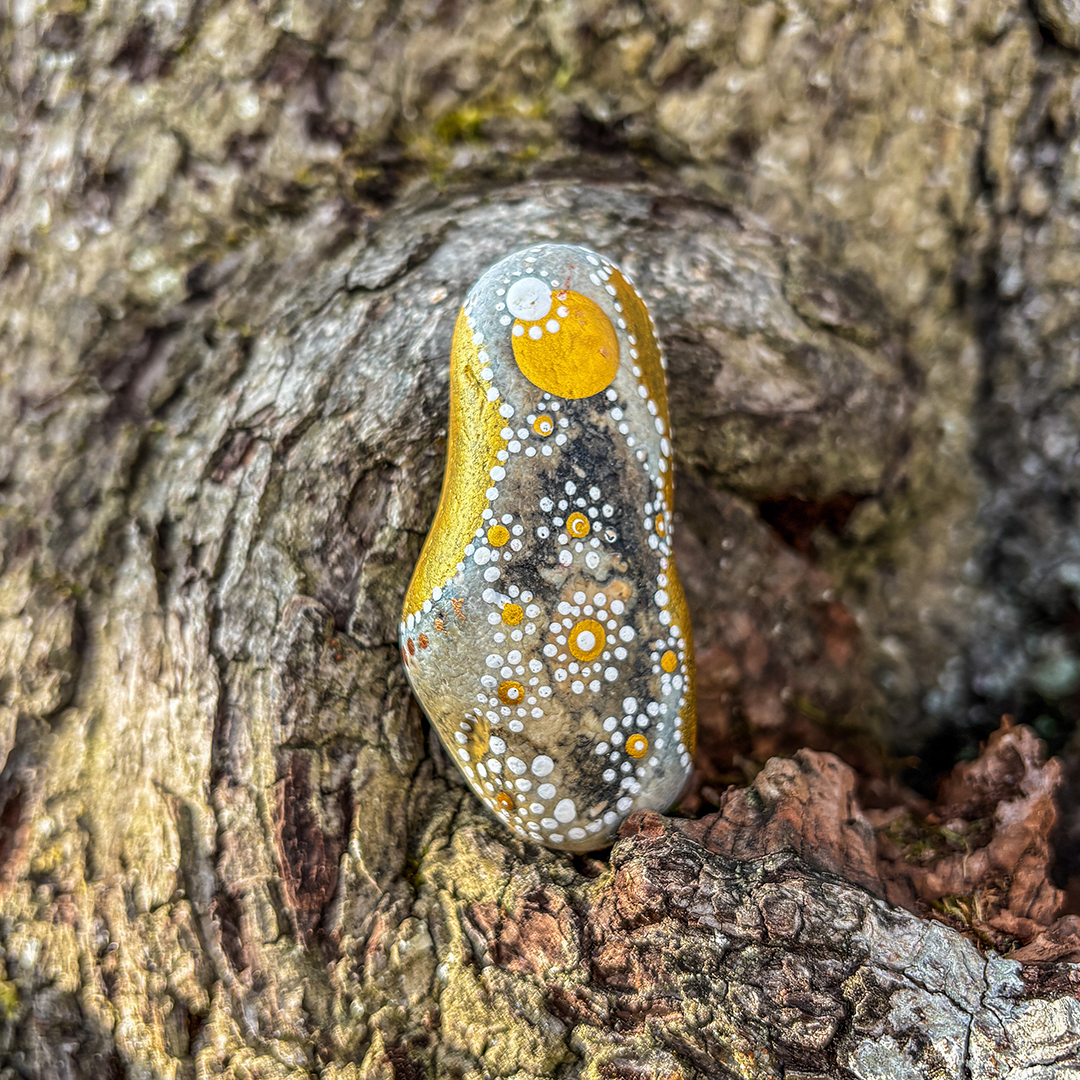 Bemalter Stein mit Engel vor Rinde