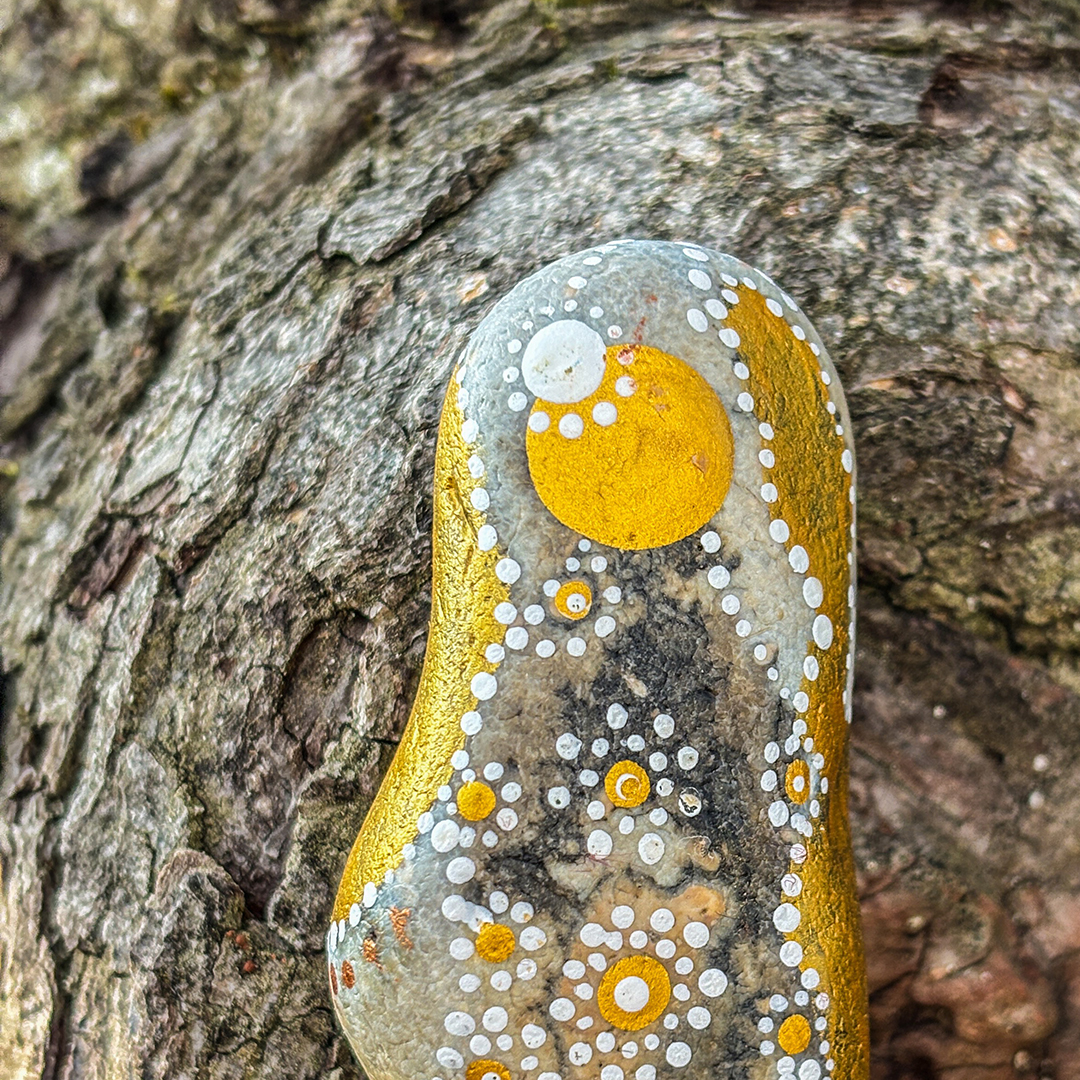 Bemalter Stein mit Engel vor Rinde in Nahaufnahme