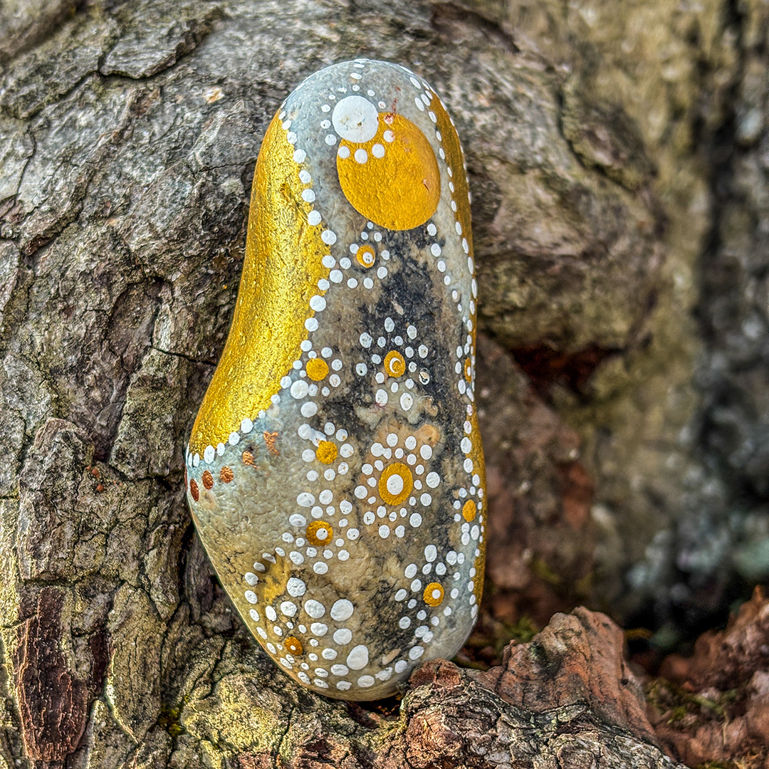 Bemalter Stein mit Engel vor Rinde