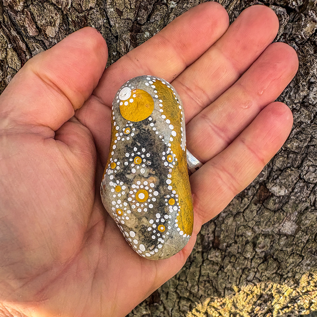 Bemalter Stein mit Engel auf Handfläche liegend