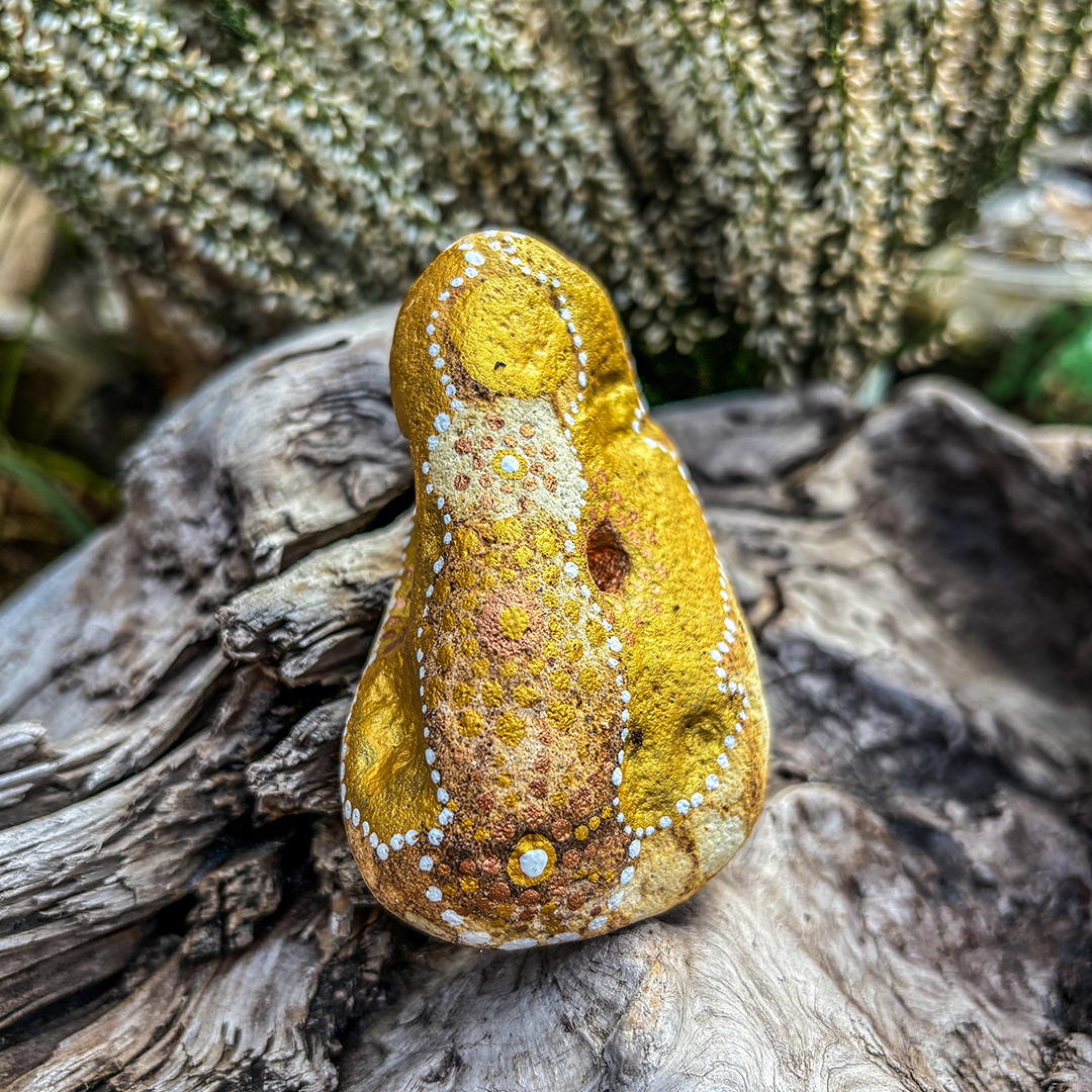 Bemalter Stein mit Engel vor weißer Erikapflanze