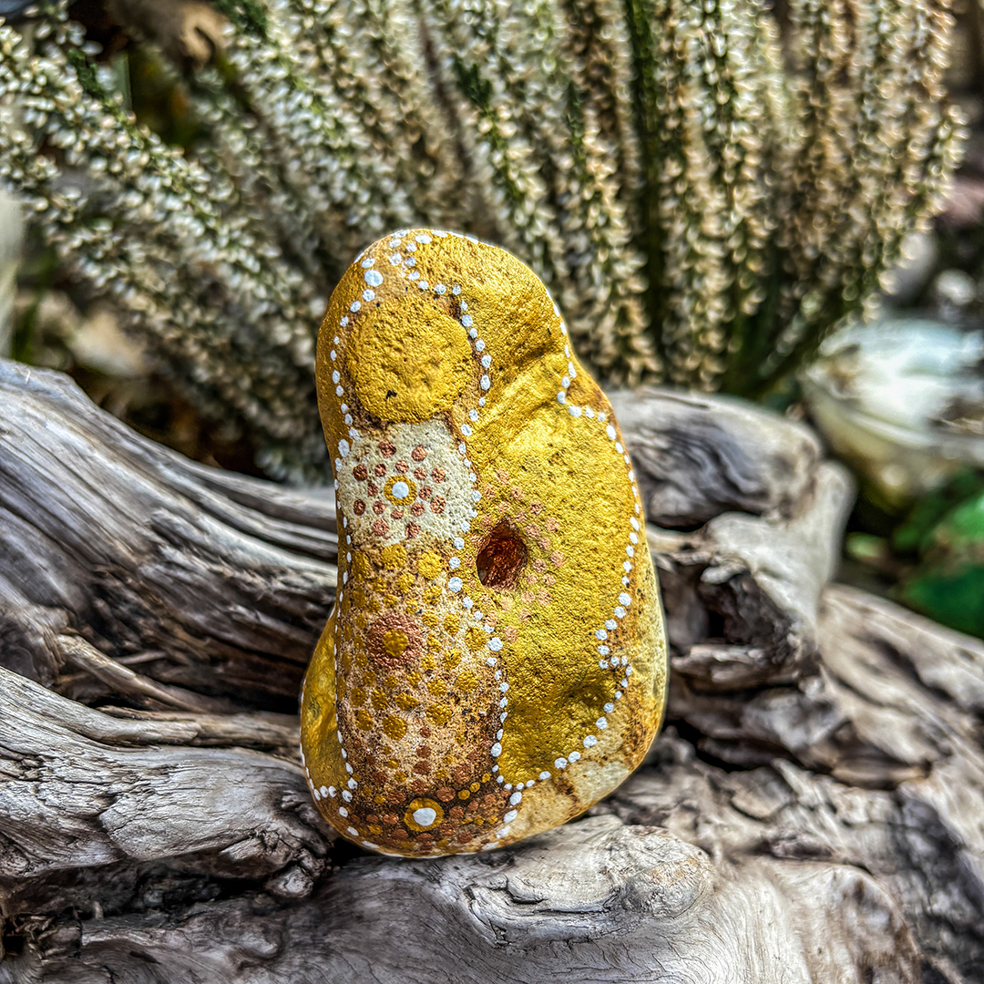 Bemalter Stein mit Engel vor weißer Erikapflanze