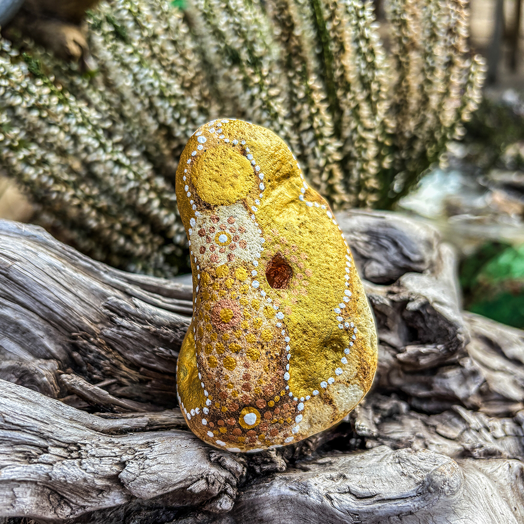 Bemalter Stein mit Engel vor weißer Erikapflanze