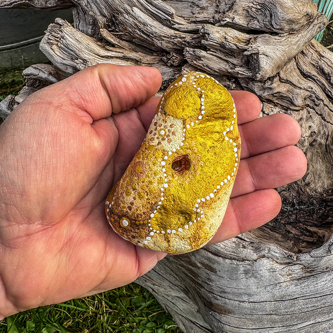 Bemalter Stein mit Engel auf Handfläche liegend