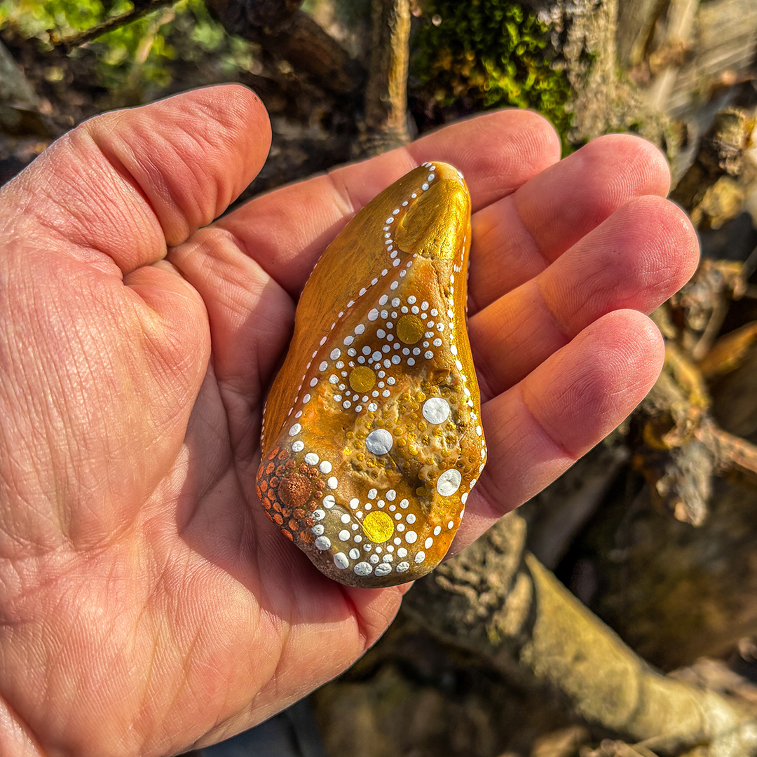 Bemalter Stein mit Engel in Handfläche liegend
