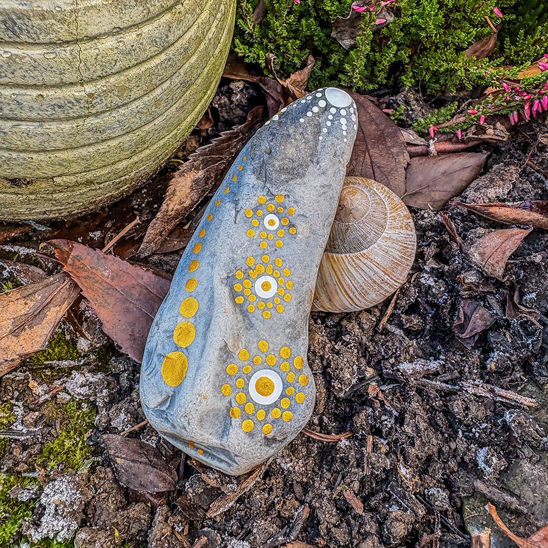 In Dot Painting Technik bemalter Stein neben Schneckenhaus