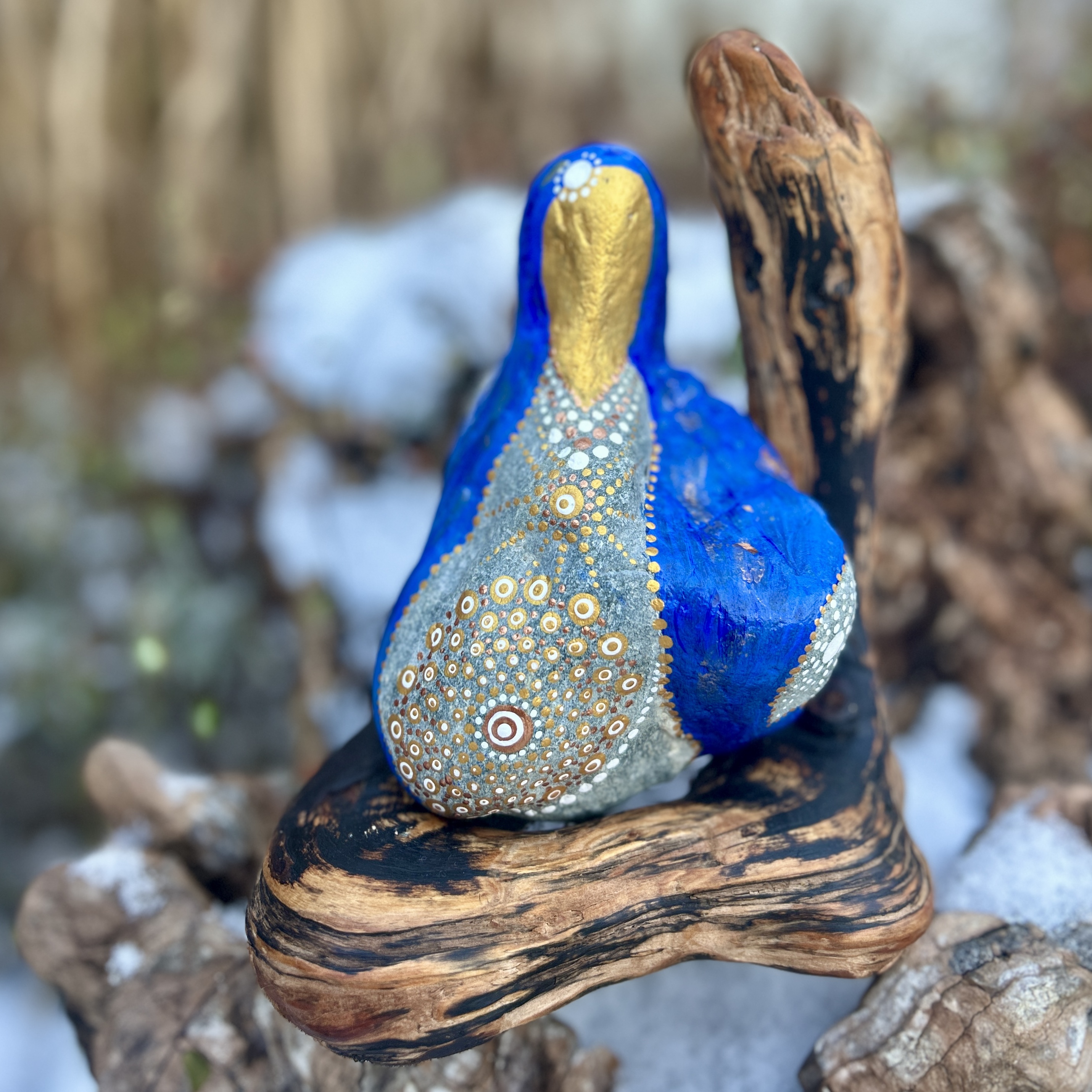 Stein in blau und gold in der Gestalt von Mutter Maria bemalt auf Treibholz stehend