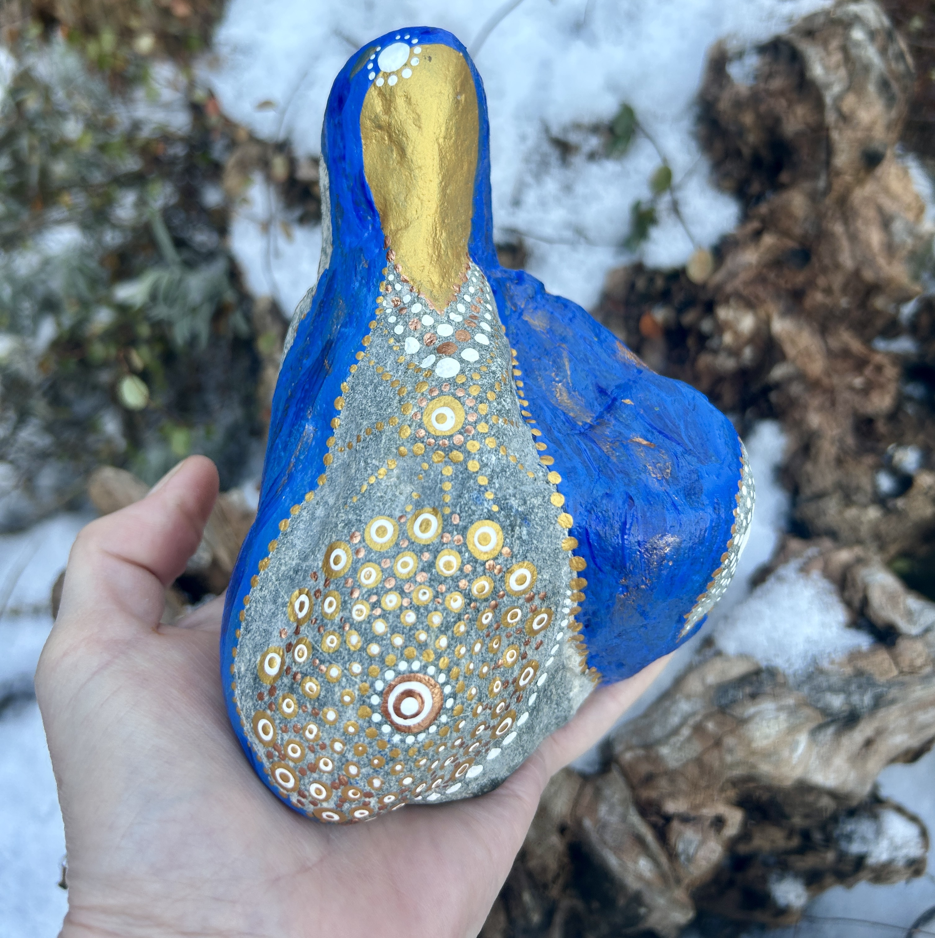 Stein in blau und gold in der Gestalt von Mutter Maria bemalt auf Handfläche stehend