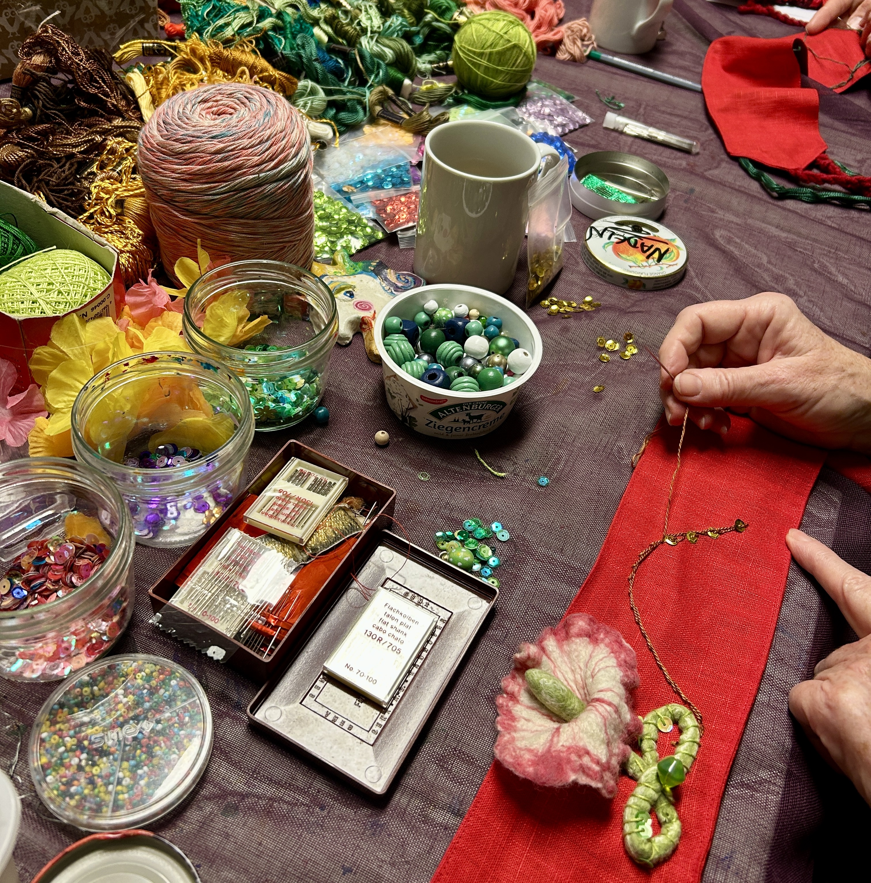 Stickarbeit mit Stickgarn und Perlen auf einem Tisch liegend