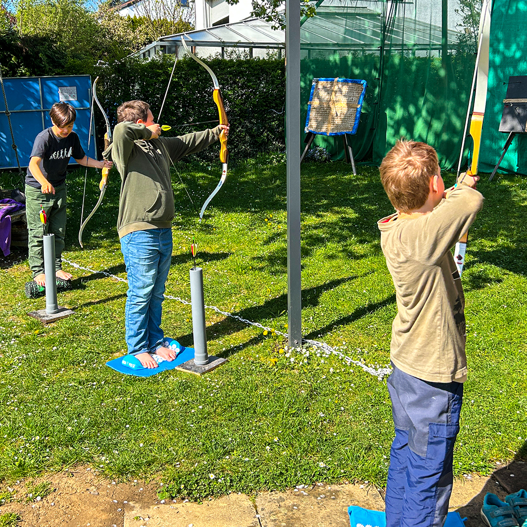Mehrere Kinder beim Bogenschießen