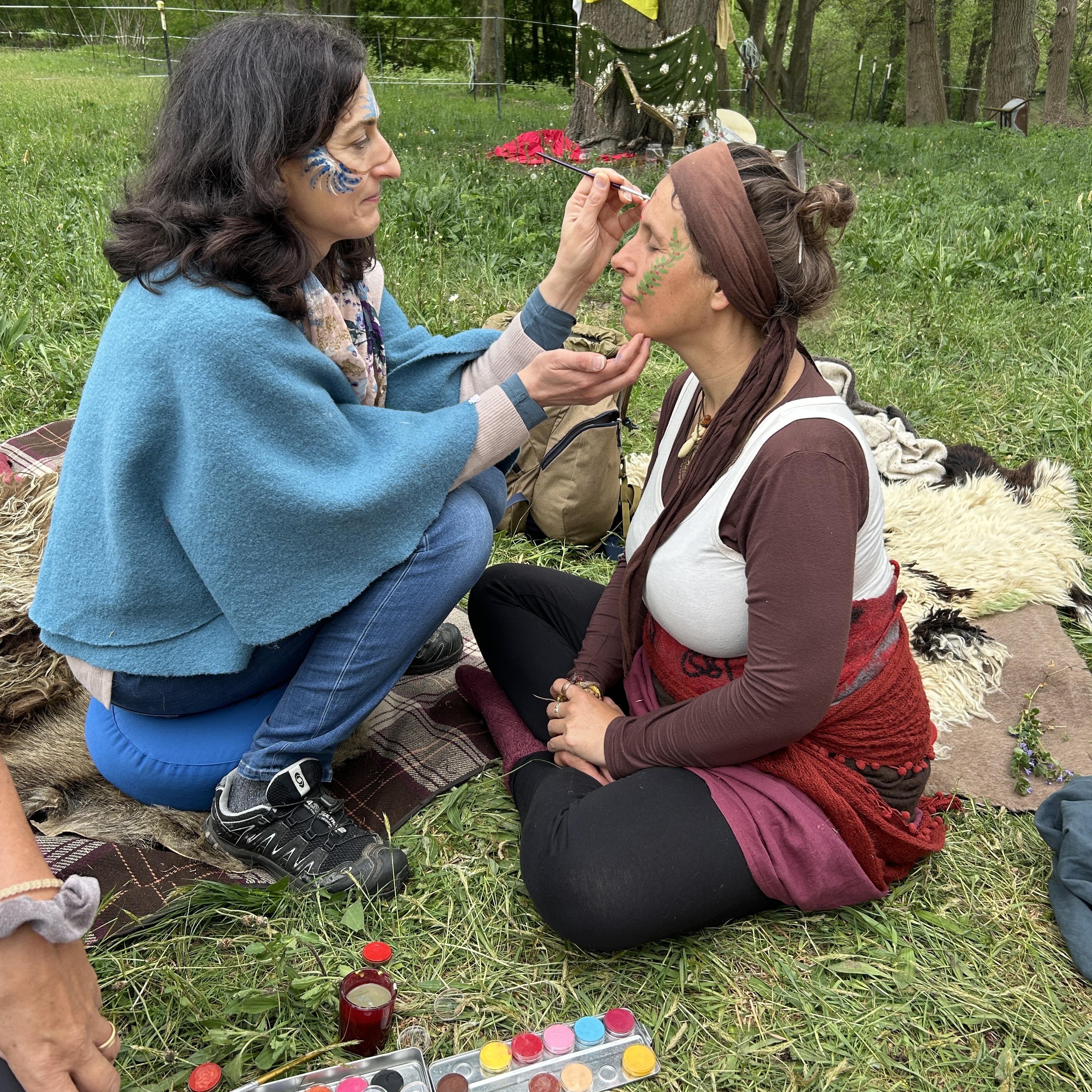 Zwei Frauen auf Boden sitzend, die gesicht bemalen