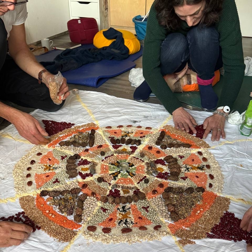 Zwei Menschen, die ein mandala aus Körnern auf Boden legen