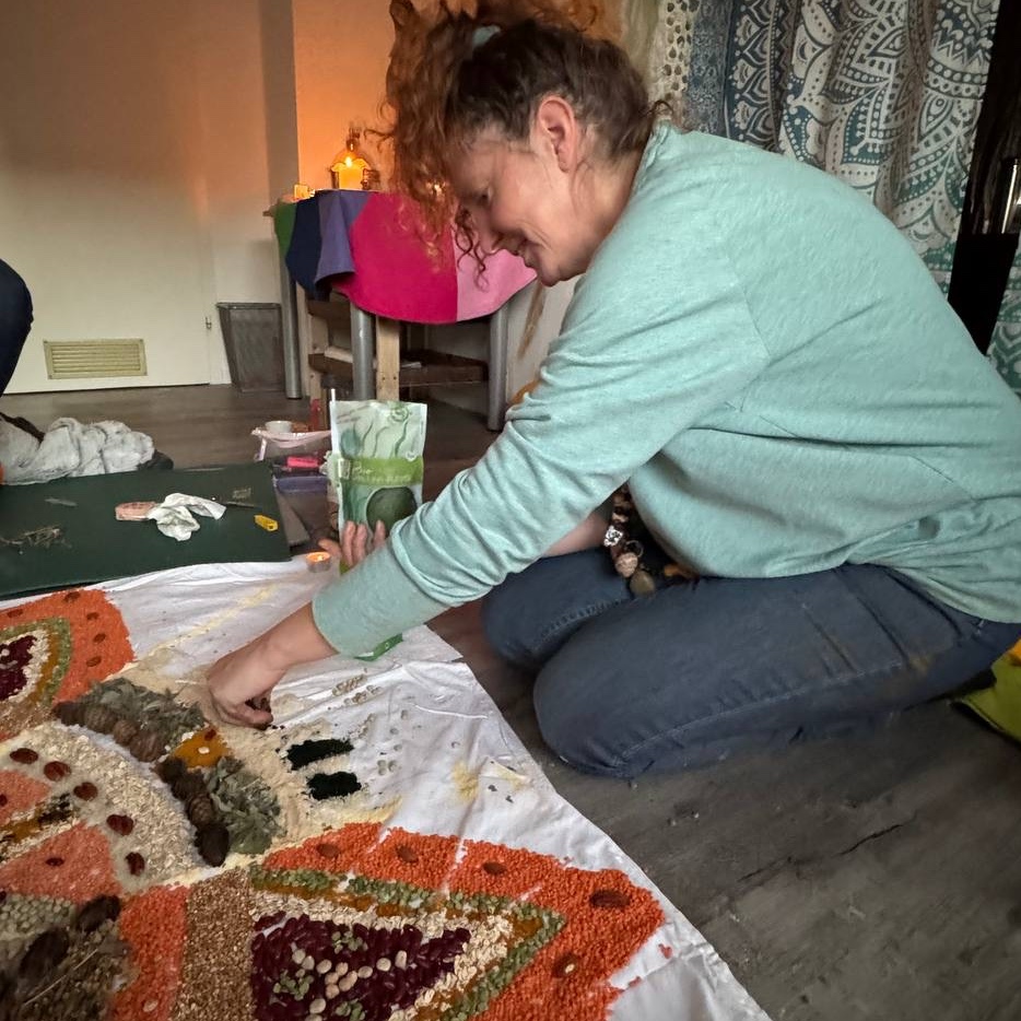 Frau, die ein mandala aus Körnern auf Boden legt