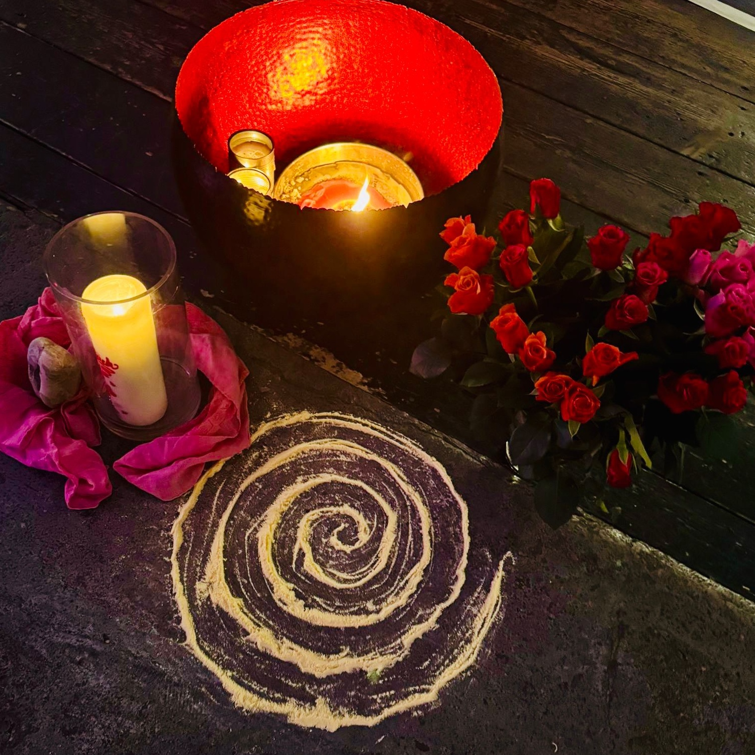 Kerze und Blumenstrauß mit roten Rosen sowie Spirale aus Maismehl auf Boden