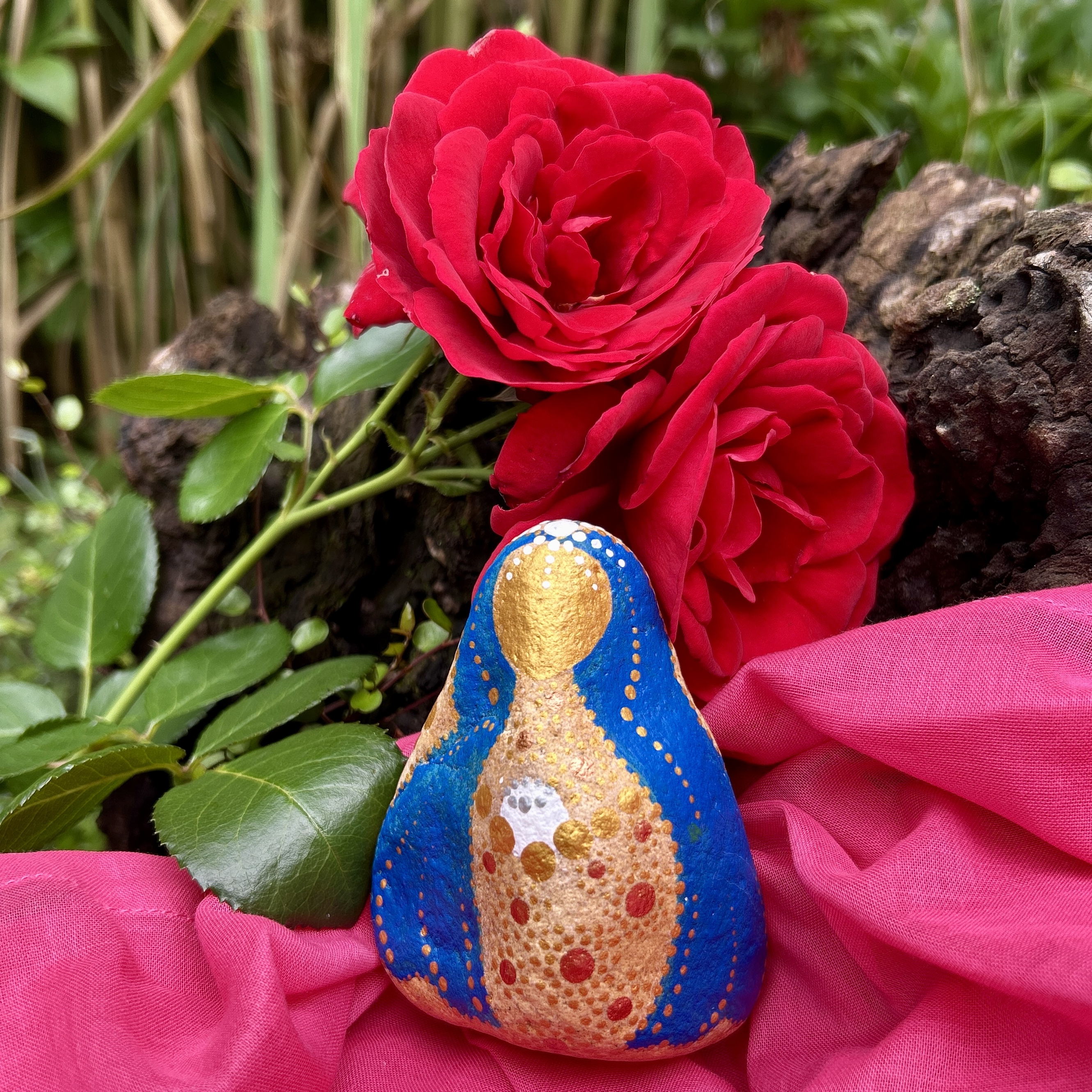 Mutter Maria aus Stein vor roten Rosen